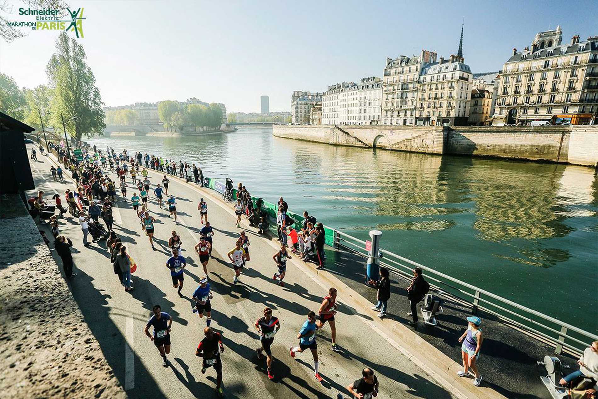 A crowd of runners making their way along the banks of the River Seine.