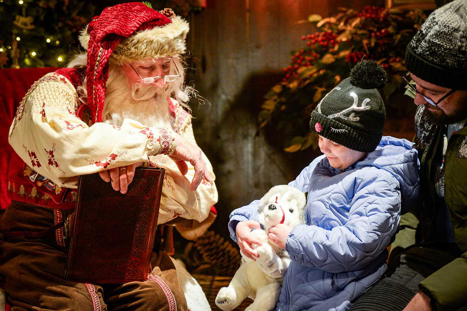 Julia holding onto a husky plush doll as she talks to Santa in his grotto.