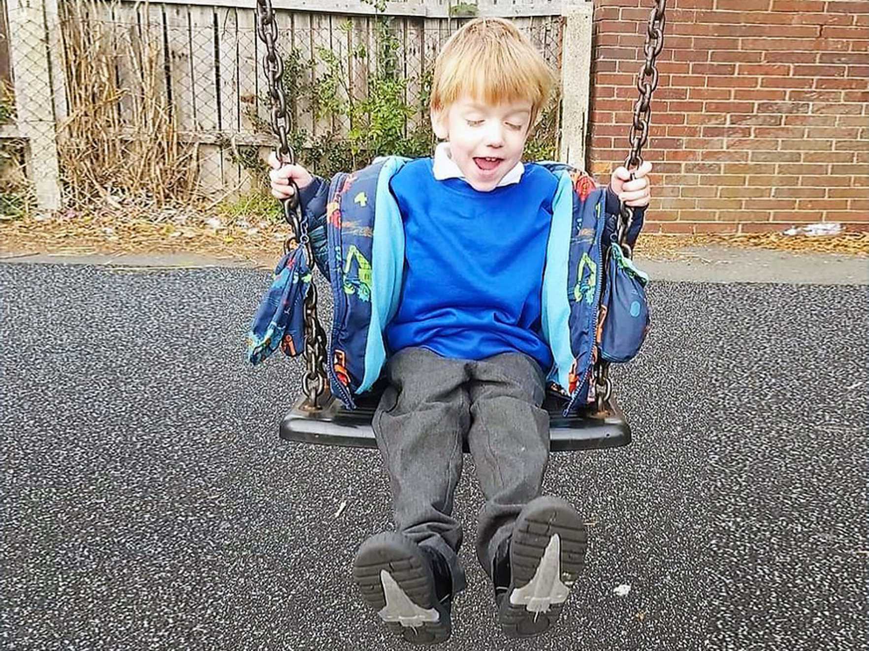 A smiling Aiden playing on the swings.