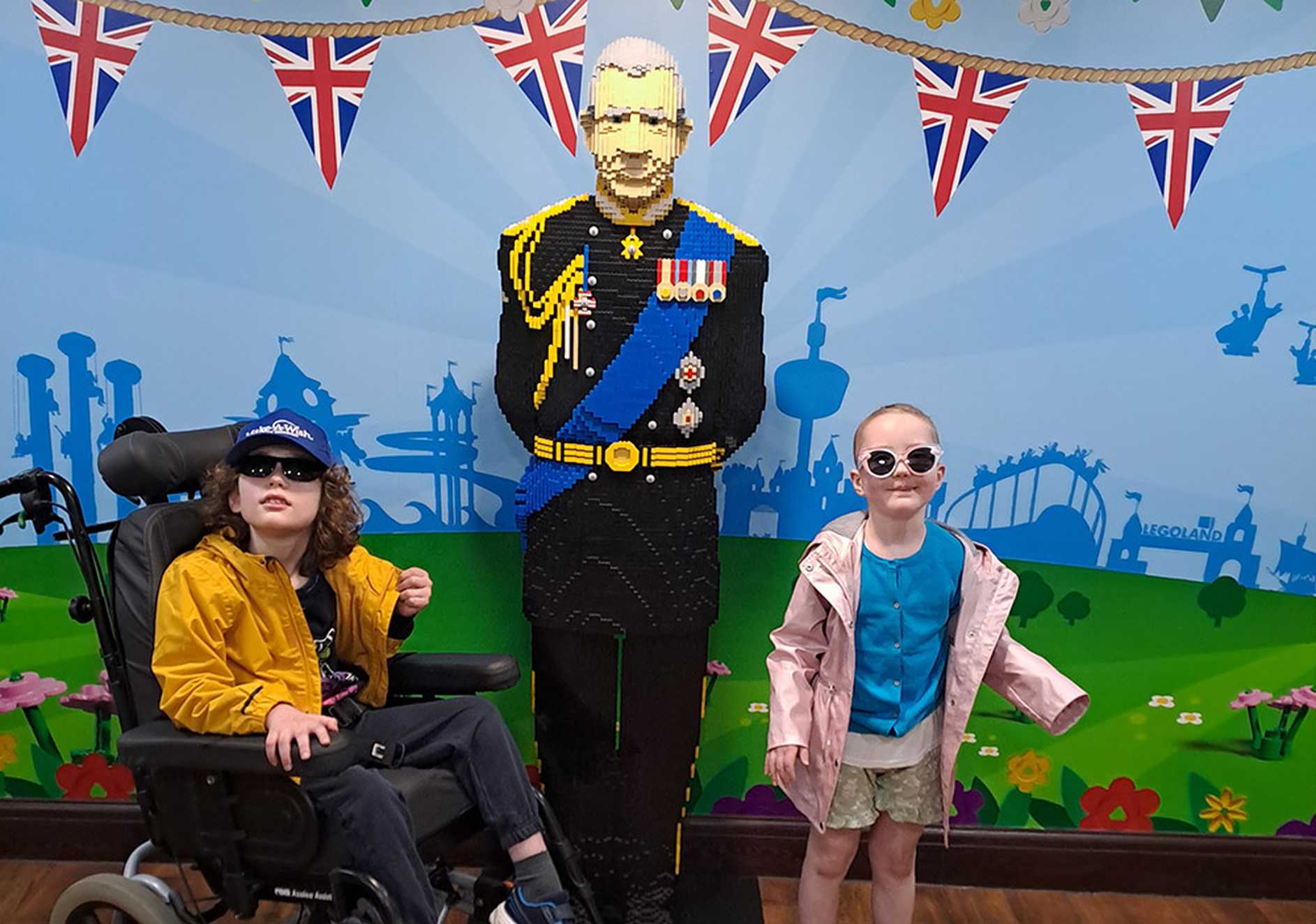 Penelope, and Lucas in his chair are either side of a lifesize Lego statue of King Charles