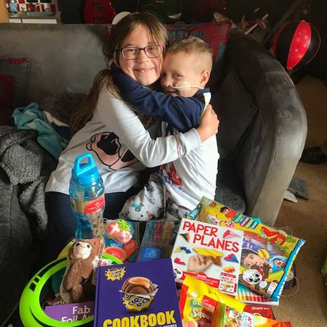 Zakk hugging sister, Annabelle with all his gifts laid out in front of them.