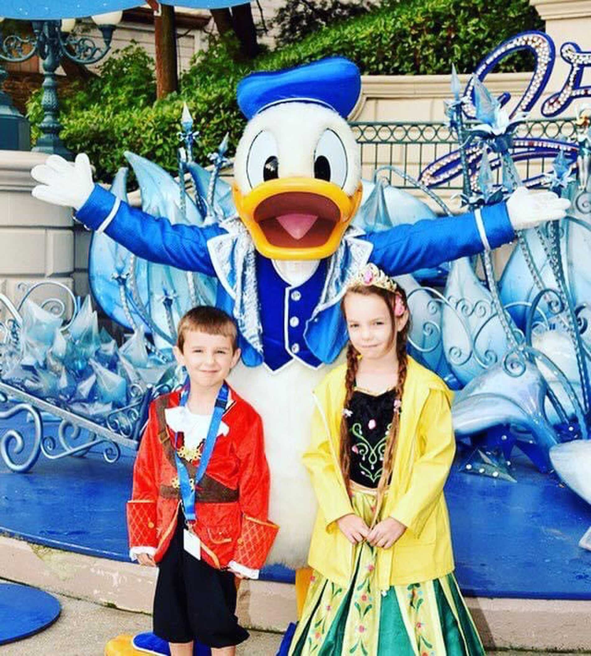 Isaac and his sister dressed as a pirate and a princess, meeting Donald Duck.