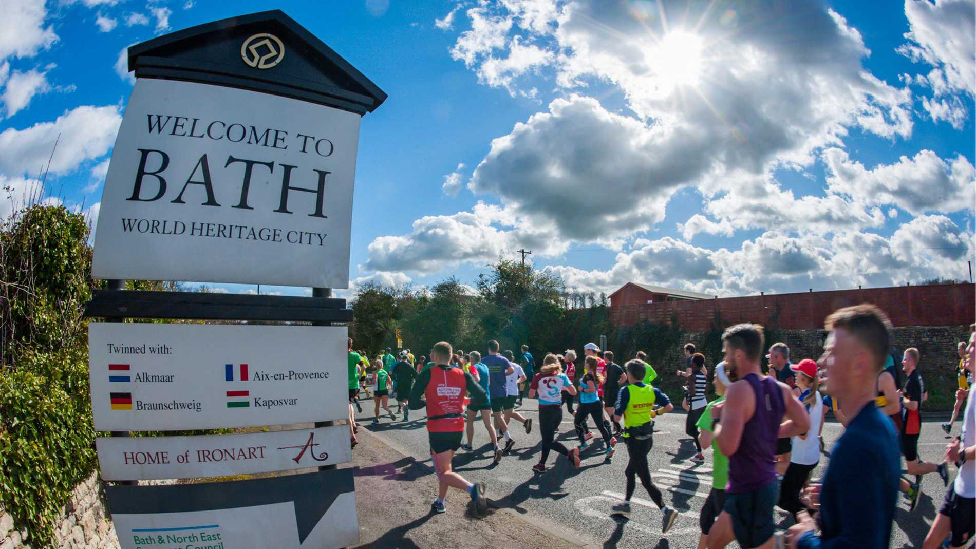 Runners passing a sign marking the entrance to the city of Bath during the Bath Half Marathon.