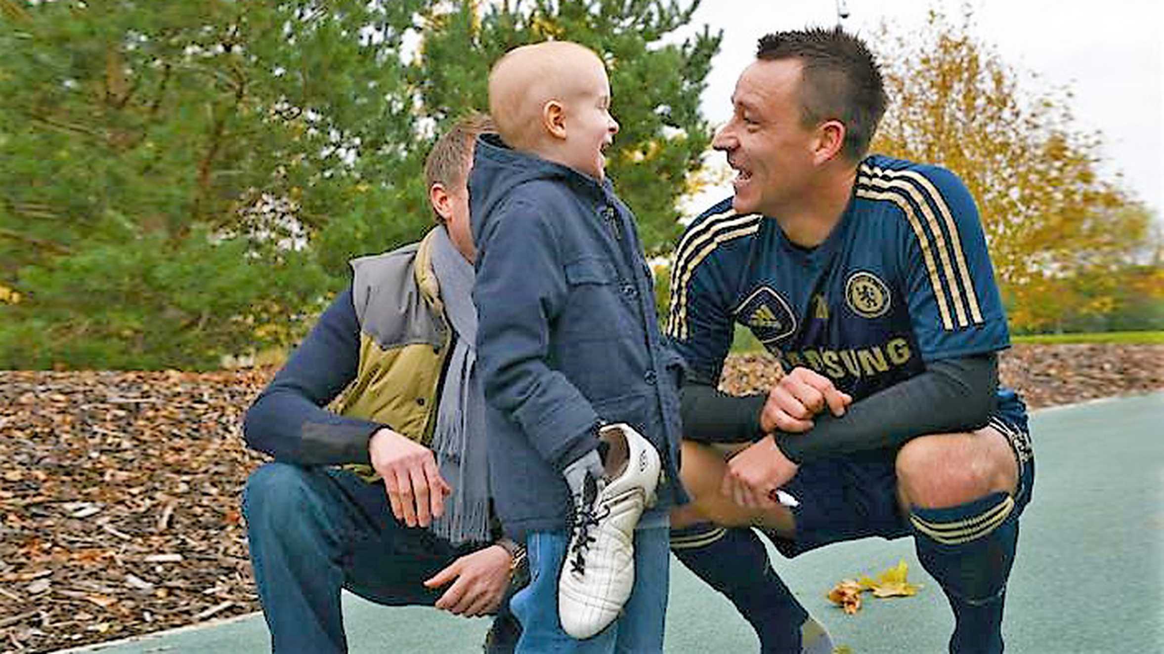 Footballer, John Terry crouched down and chatting with wish child, Oscar.