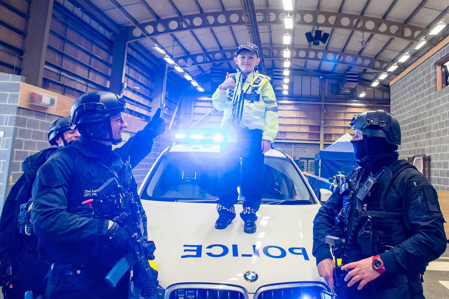 Allan standing on the bonnet of a police car with armed response officers.