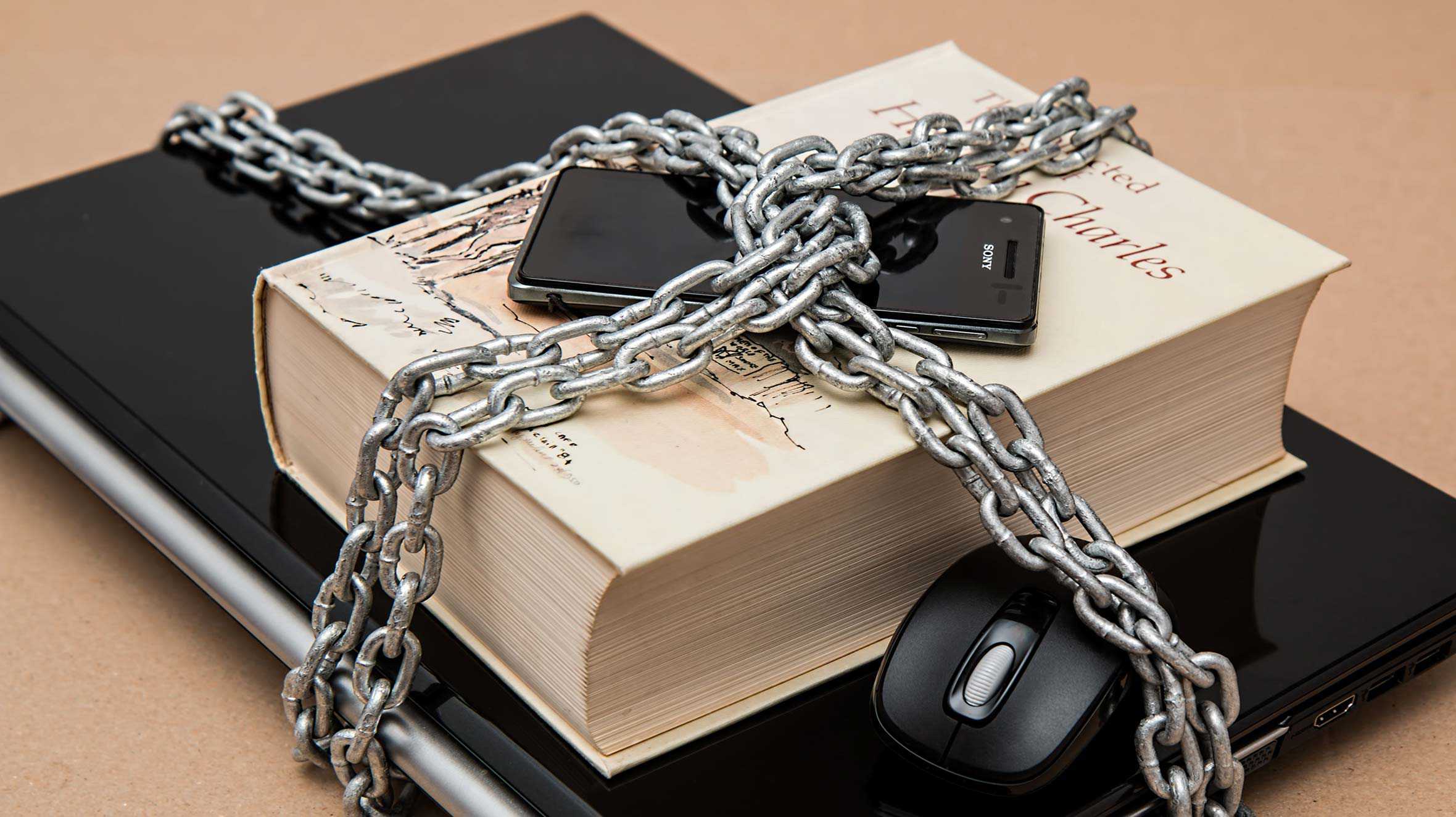 A laptop, book and mobile phone, locked up with a heavy chain and padlock.