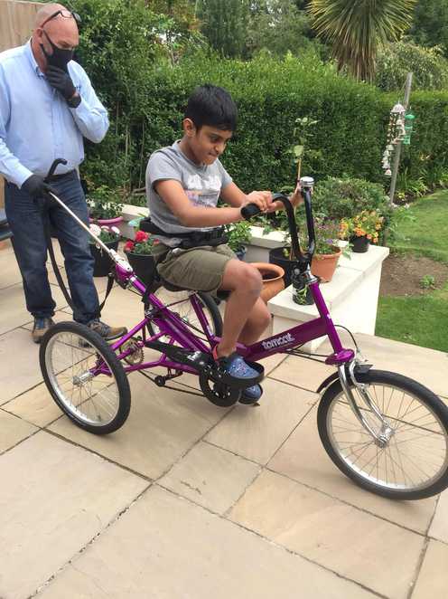 Aaryan's dad, Raj, helping him try out his new trike in their garden.