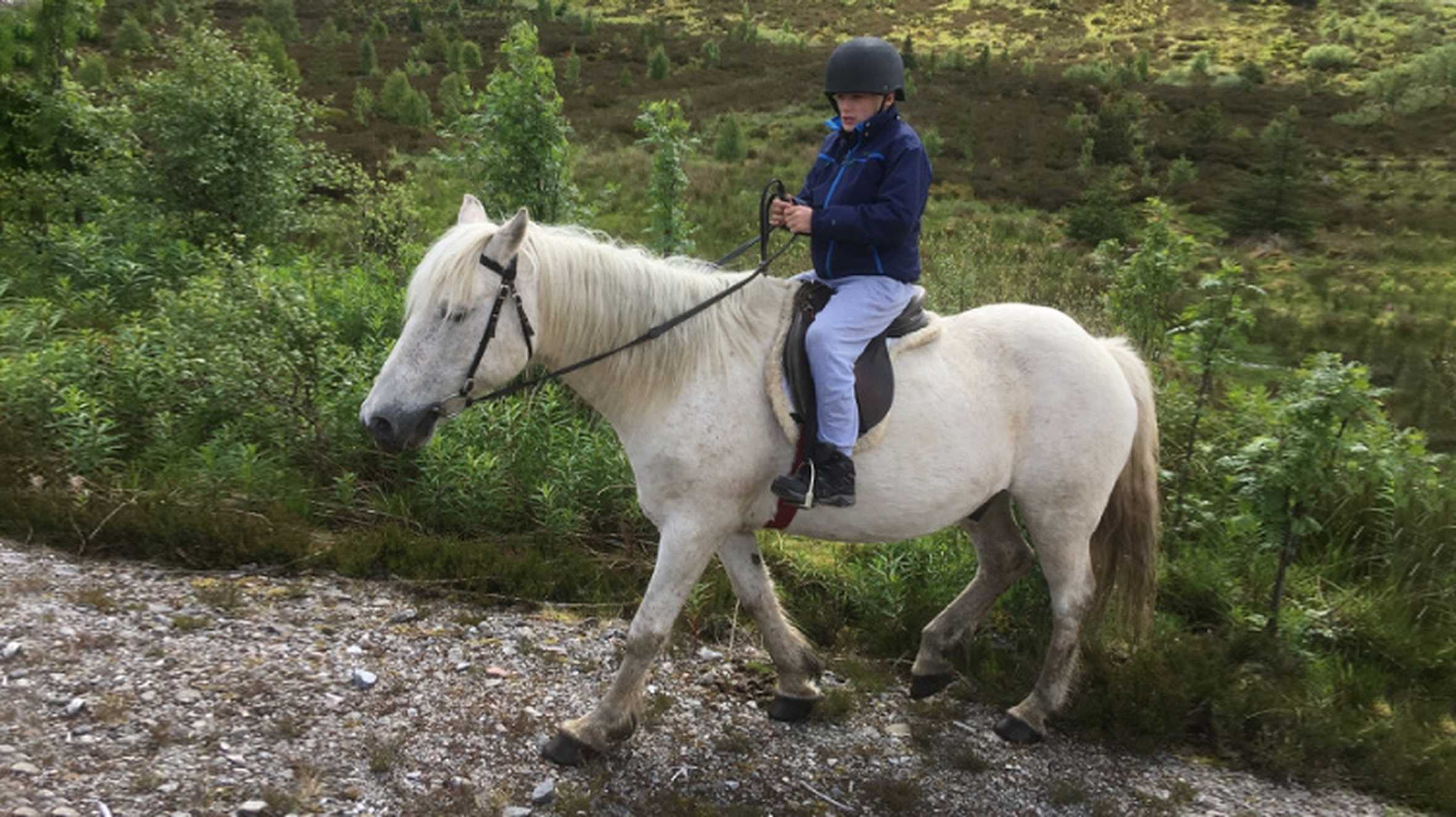 Wish child Brandon riding a horse on his wish in the Scottish Highlands