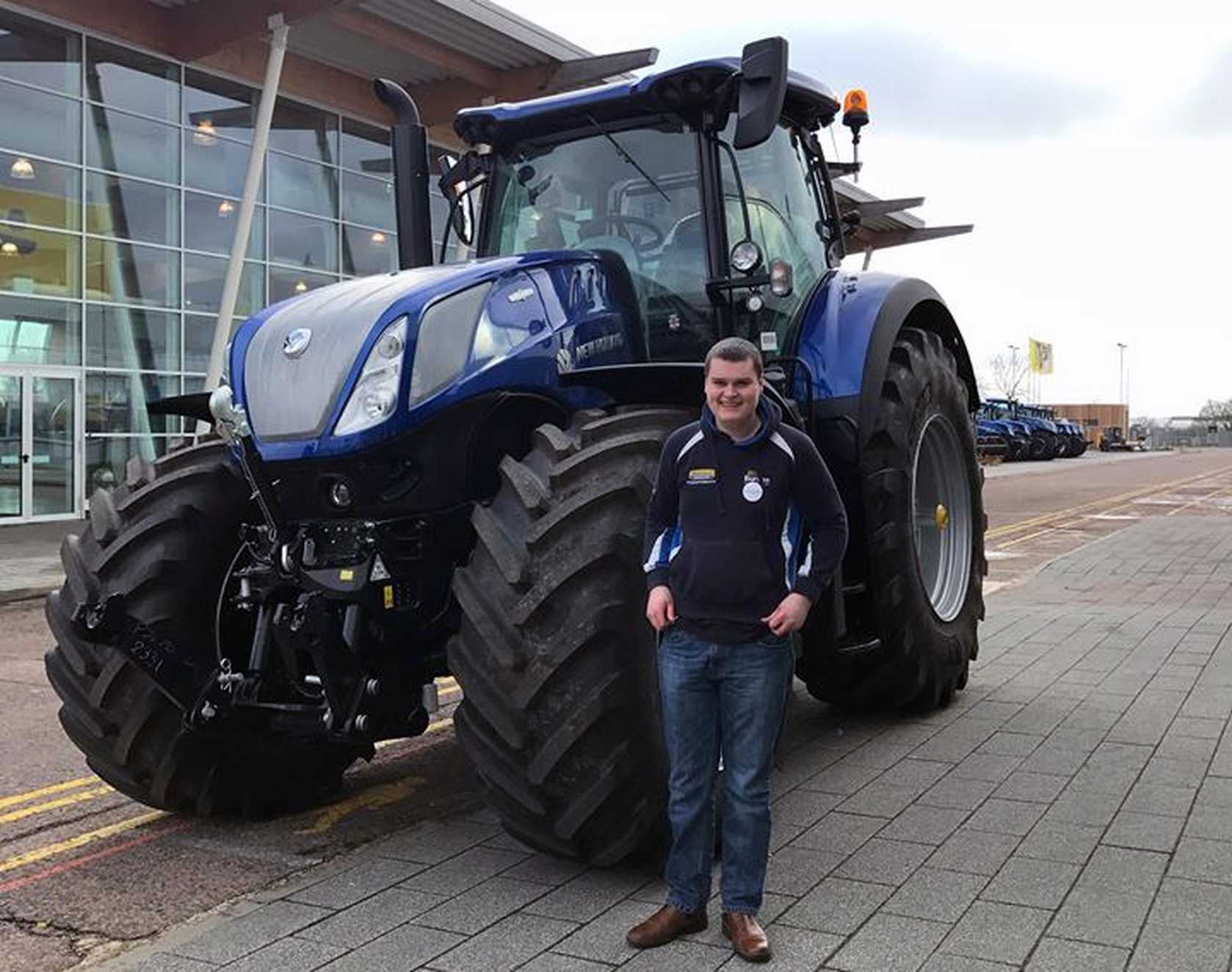 James stood in front of big blue tractor smiling