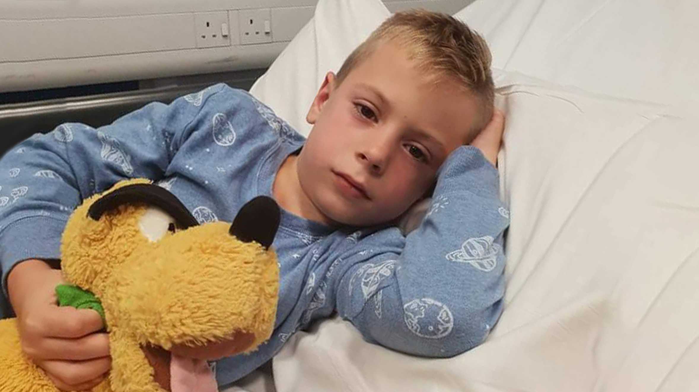 Alfie in his hospital bed, holding one of his Pluto toys.