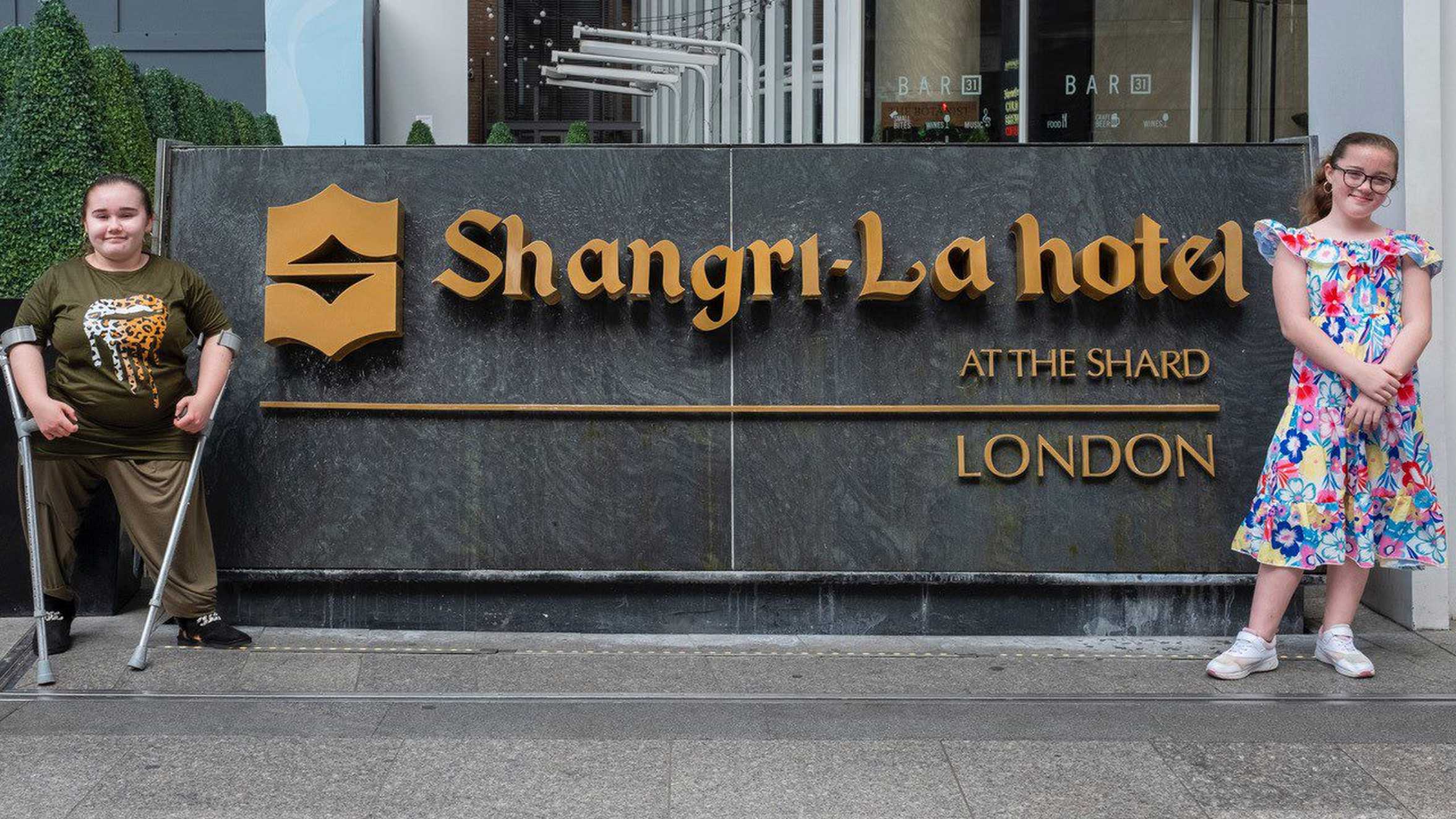 Angel and her sister, Mikayla standing by the sign in front of the Shangri-La Hotel entrance.