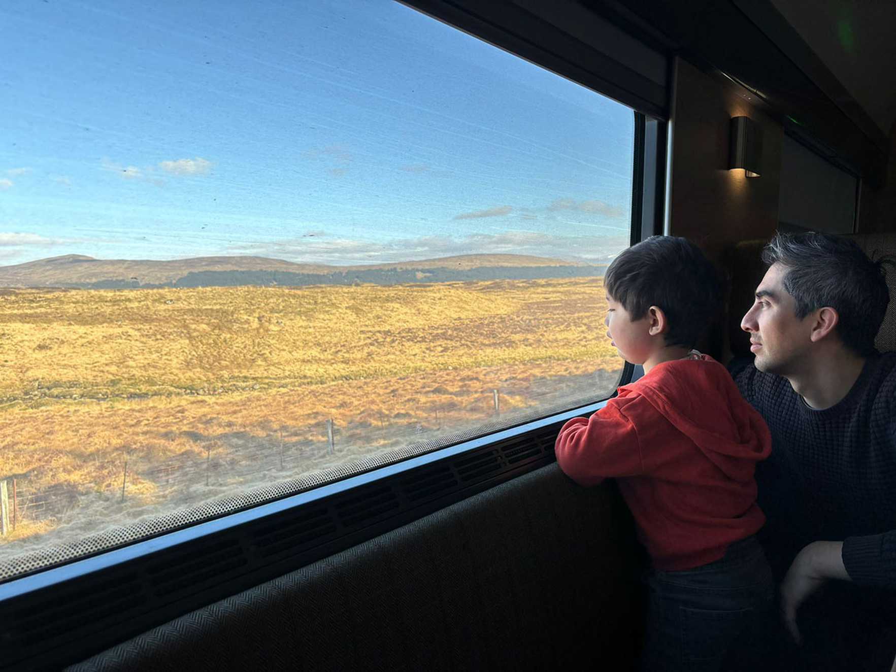 Everett looks out of the train window at the countryside with his dad