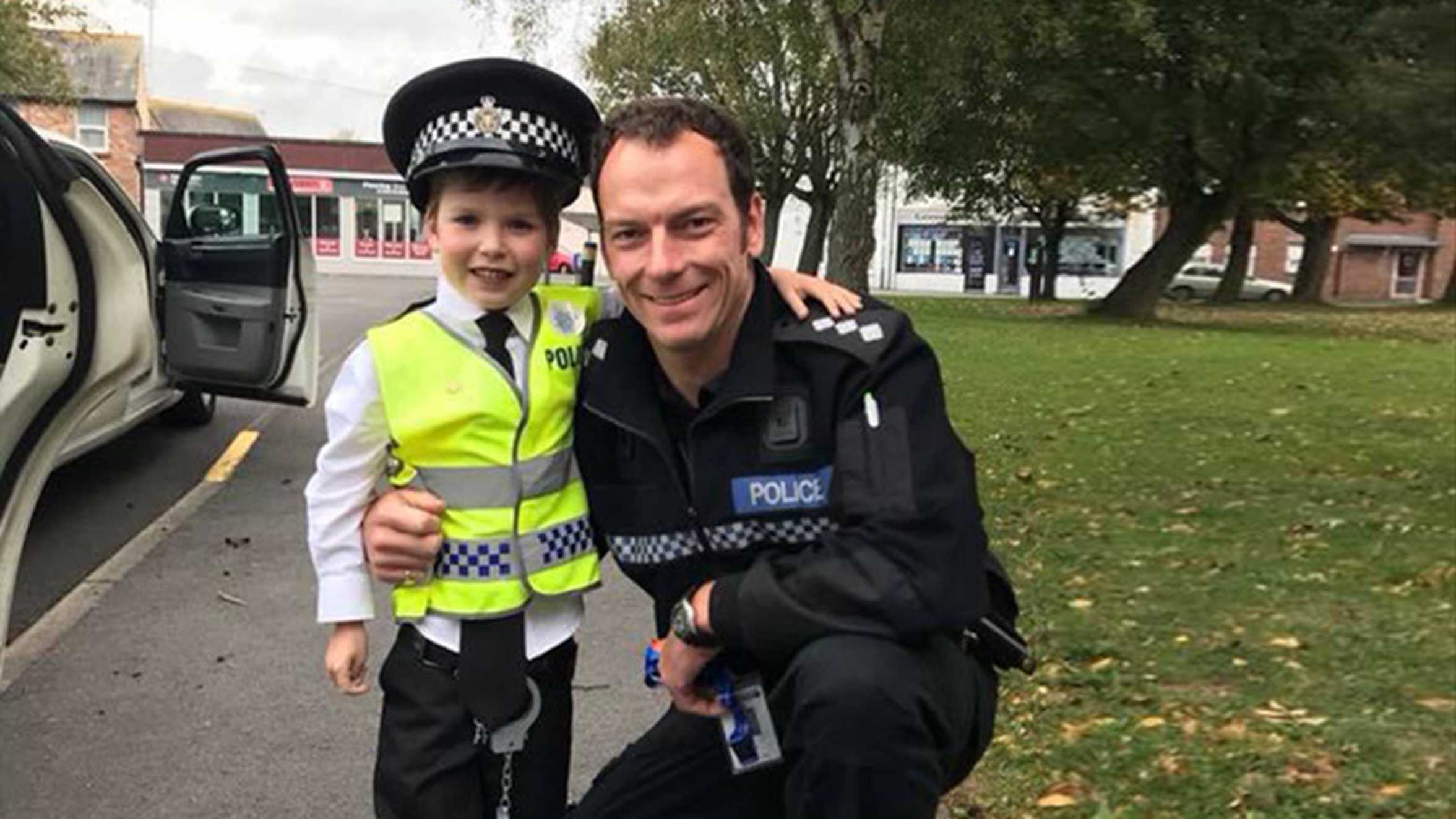 Danny wearing his own uniform and standing with a police officer