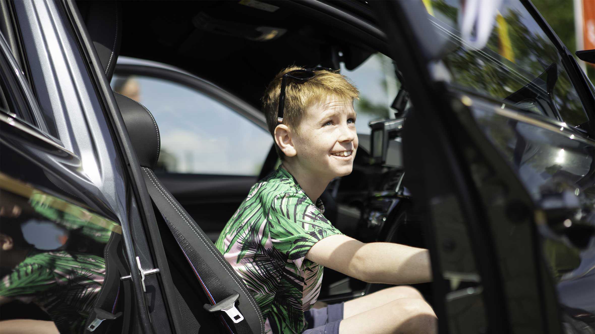 Portrait of Dewi getting out of supercar smiling and looking up