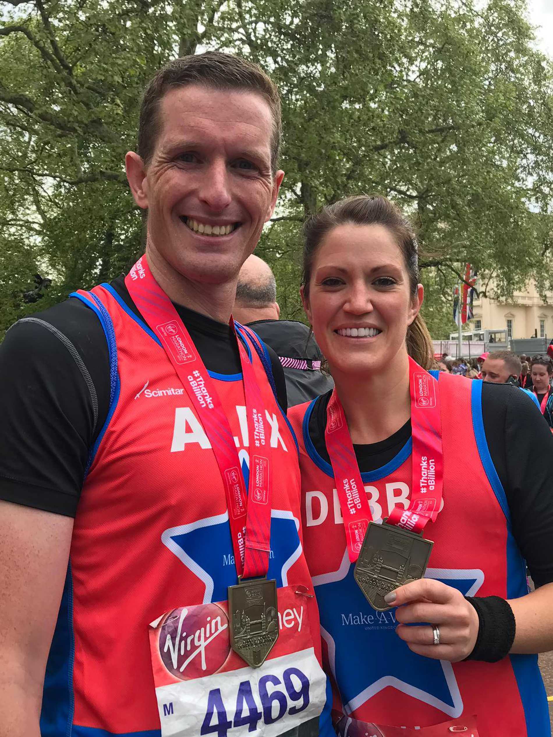 A couple of smiling runners with their London Marathon finishers medals.