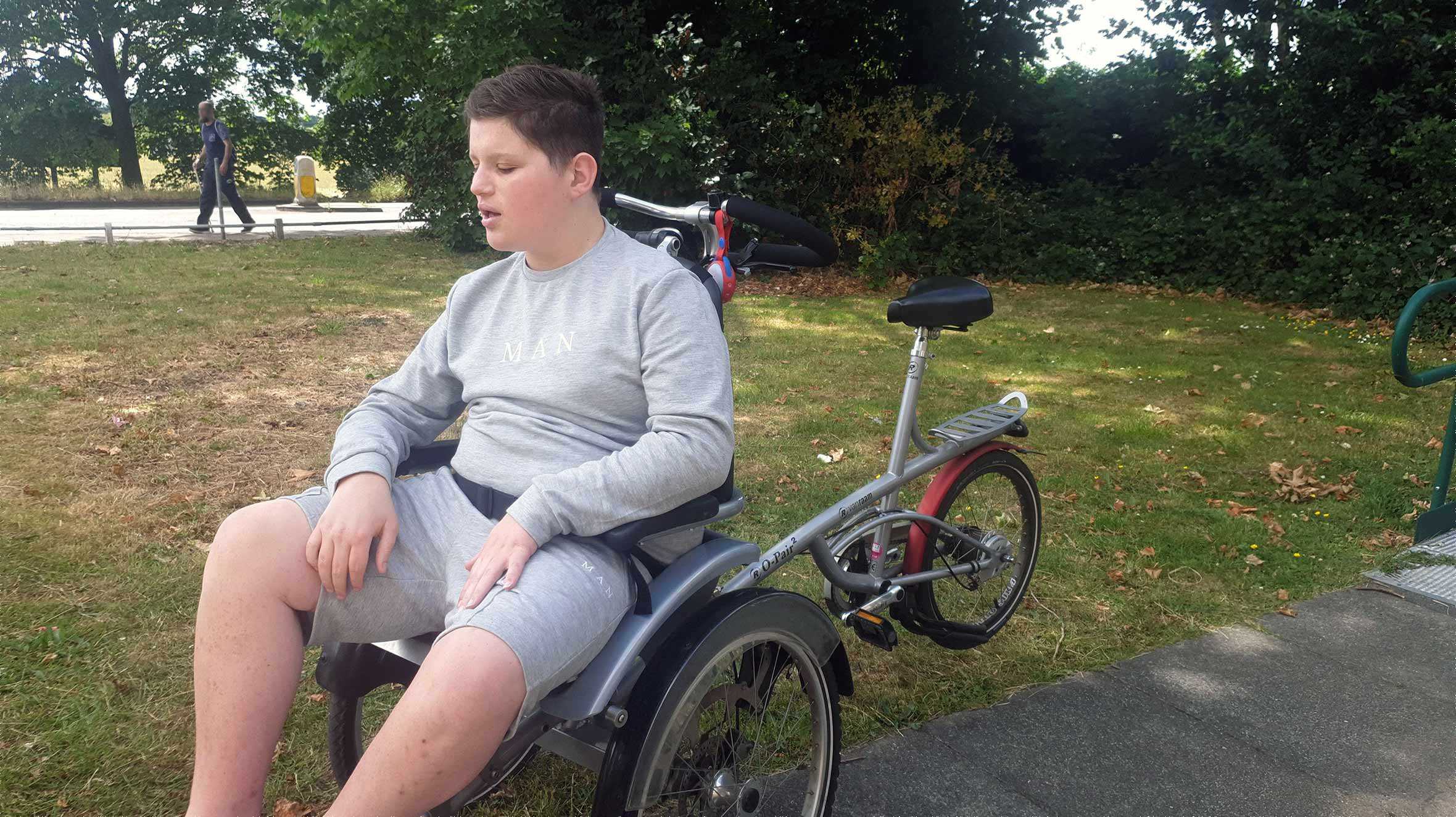 Eric sitting on his adapted bike in a London park.