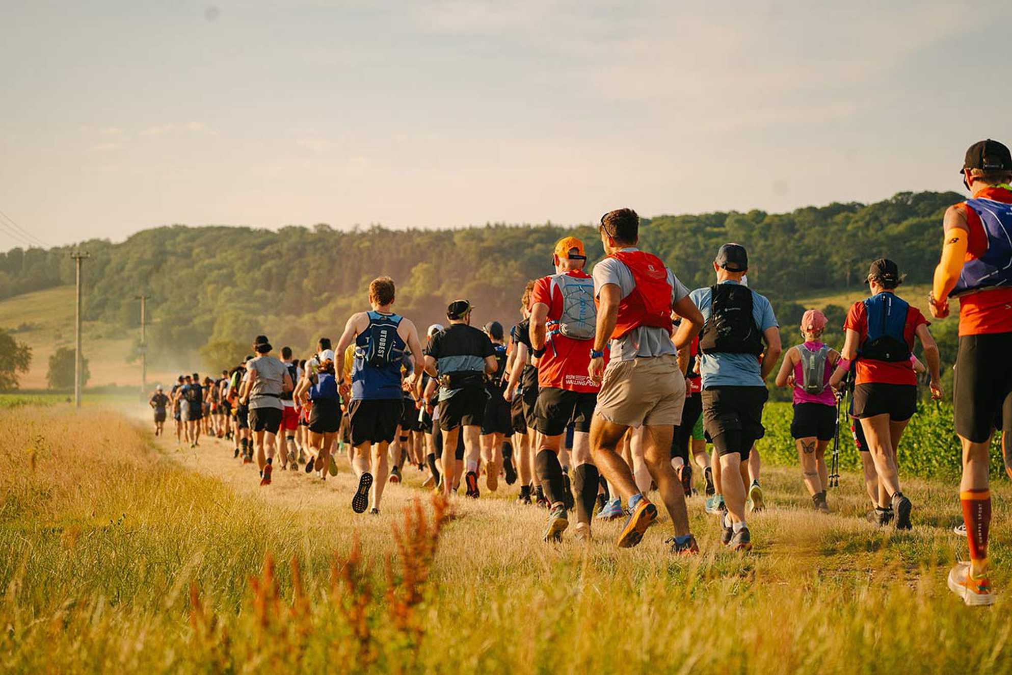 A beautifully lit photo showing a rear view of Race to the Stones participants making their way along a gravel track in the midst of the countryside.