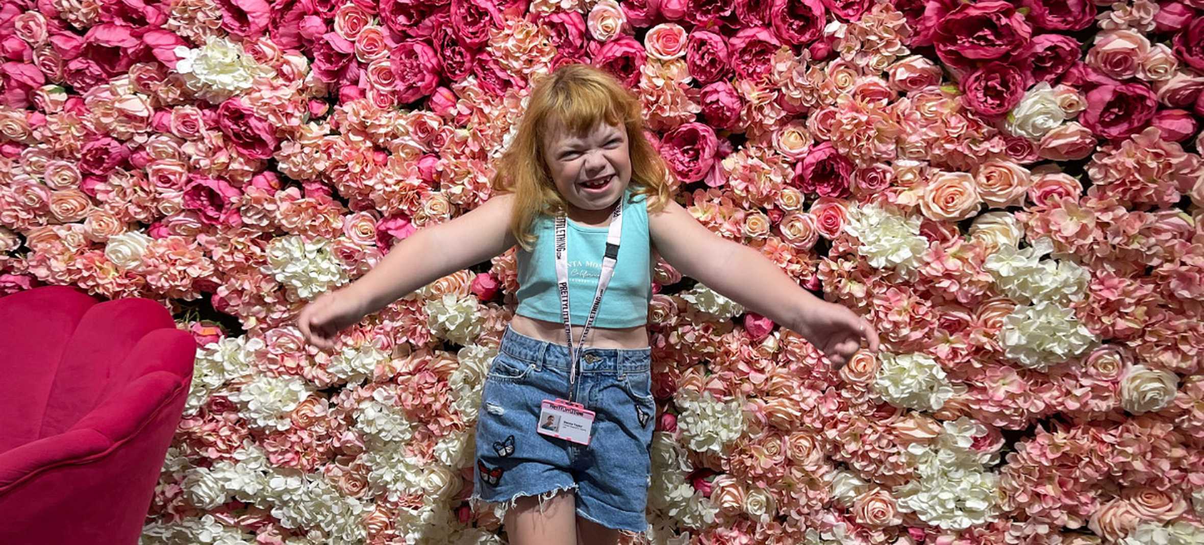 Wish child Sienna, standing in front of a wall of roses at PrettyLittleThing HQ.