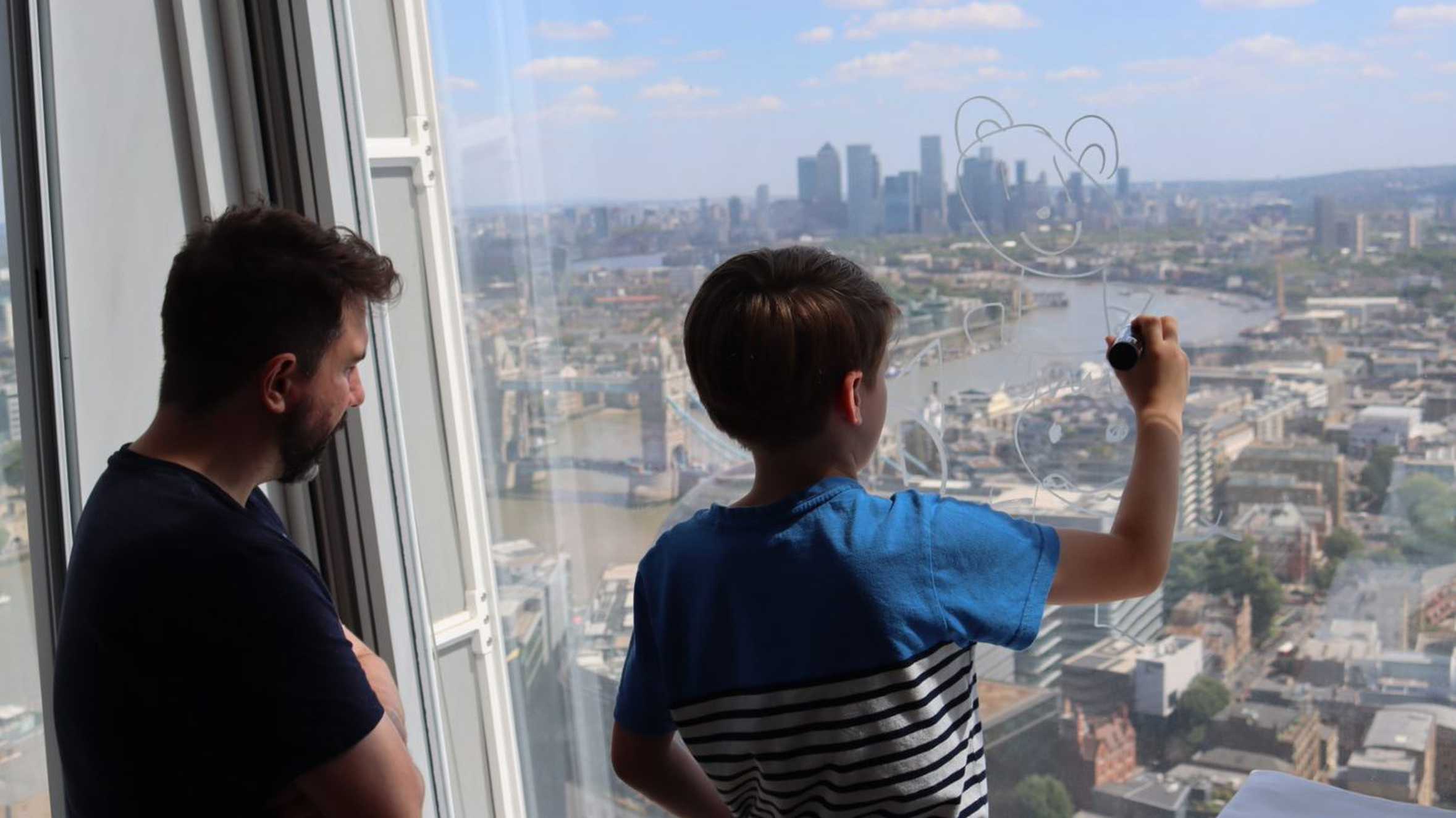 Jamie supervising as Clark draws on the hotel windows, high above the London skyline.