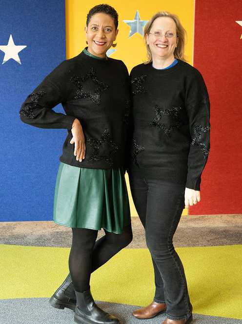 Two members of the Make-A-Wish team modelling smart sequined black jumpers from Peacocks' 2023 Christmas clothing range.