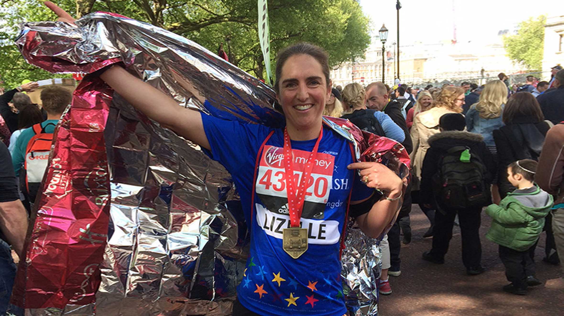 Lizelle wearing her medal and holding a celebratory hand in the air after completing the London Marathon.