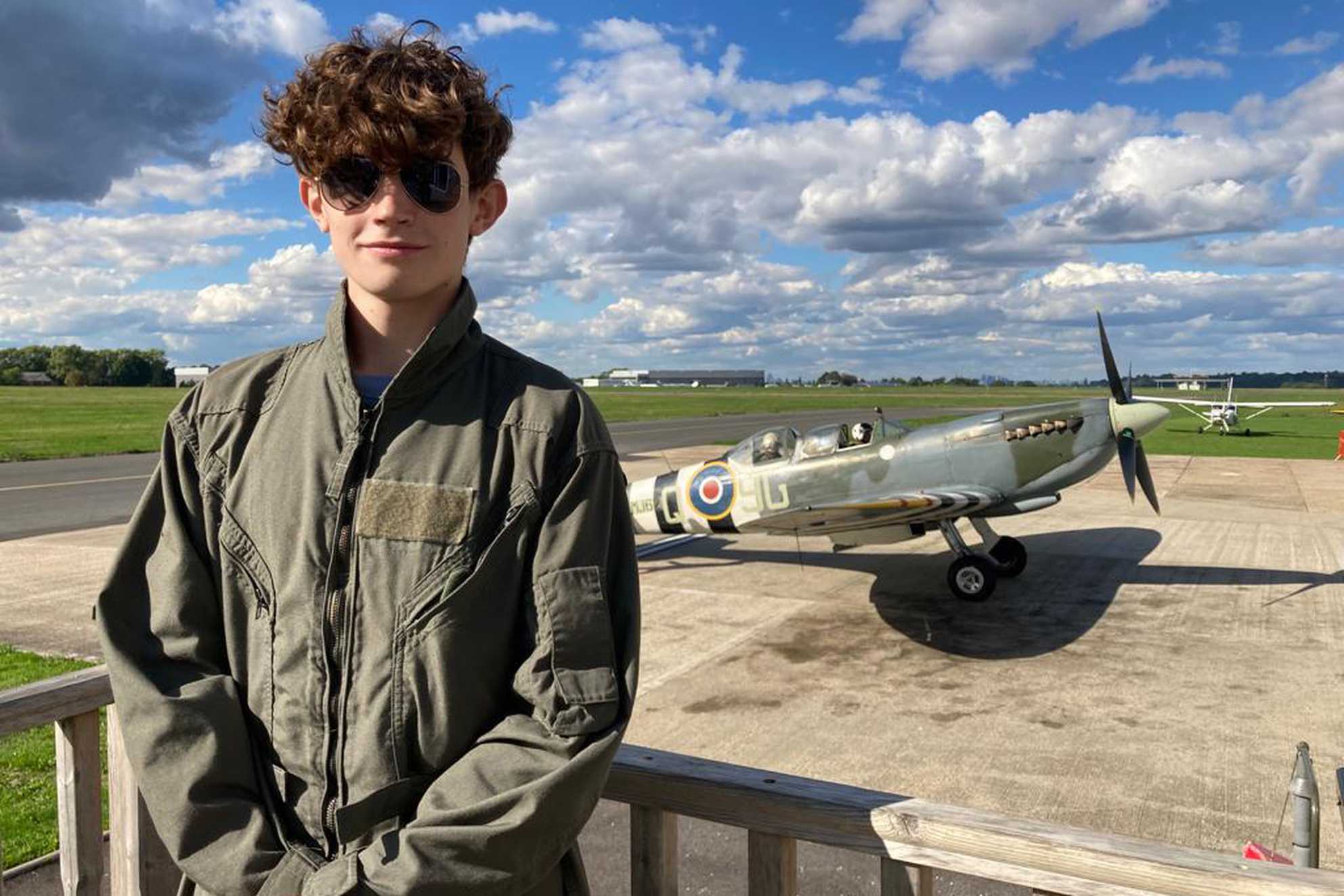 Marco standing in front of the Spitfire, looking the part in his flying suit.