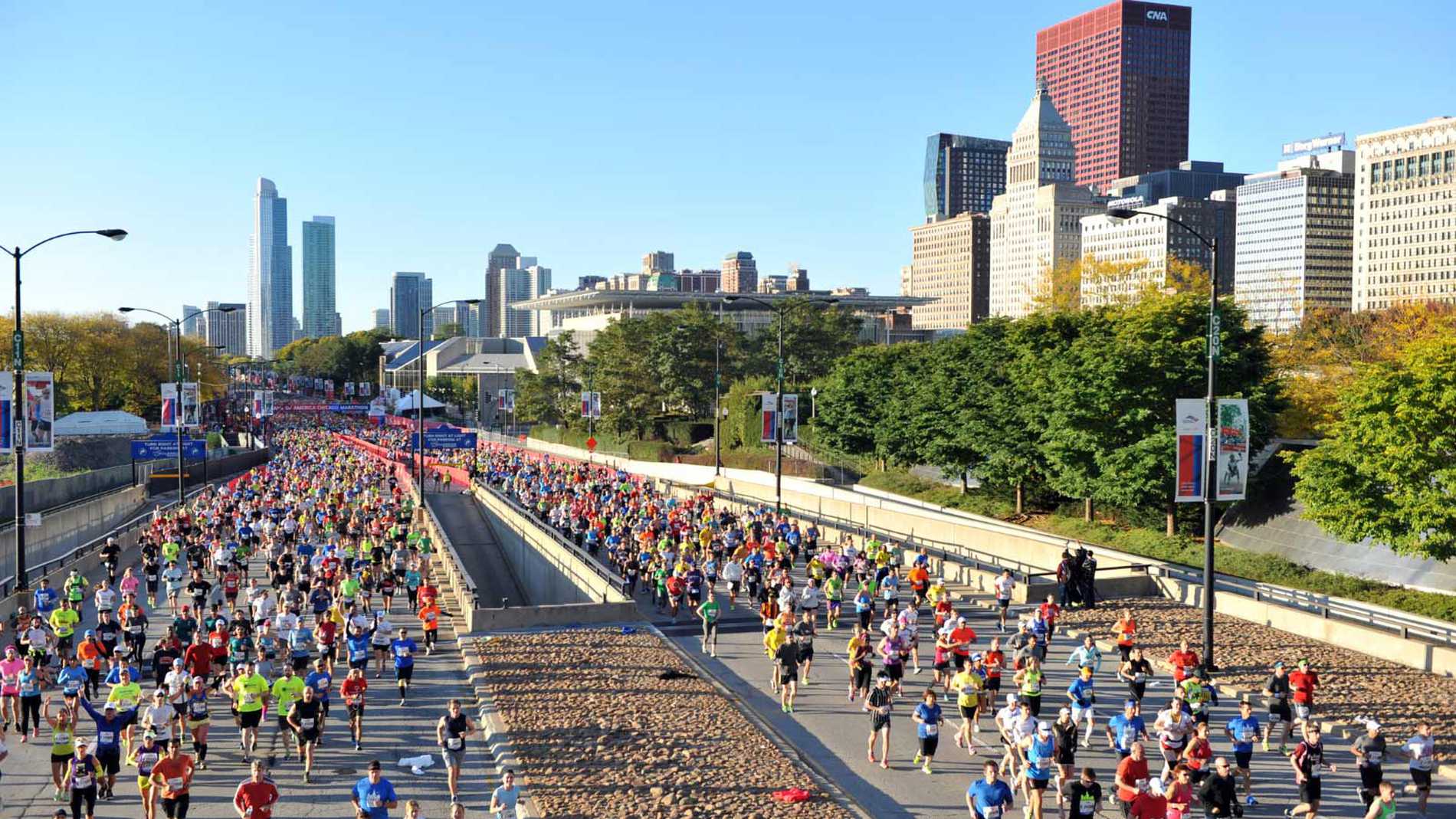 A panoramic view of the Chicago skyline as runners pass by in the foreground.