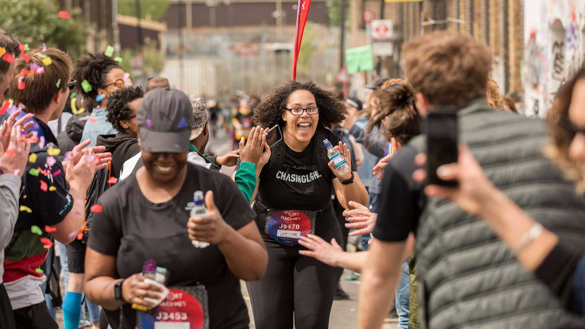 A smiling runner being cheered on by the Hackney Half Marathon crowd.