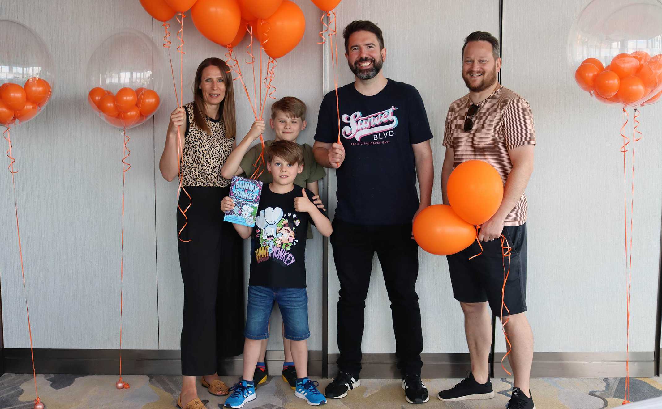 Clark and his family with Jamie, surrounded by bright orange balloons.