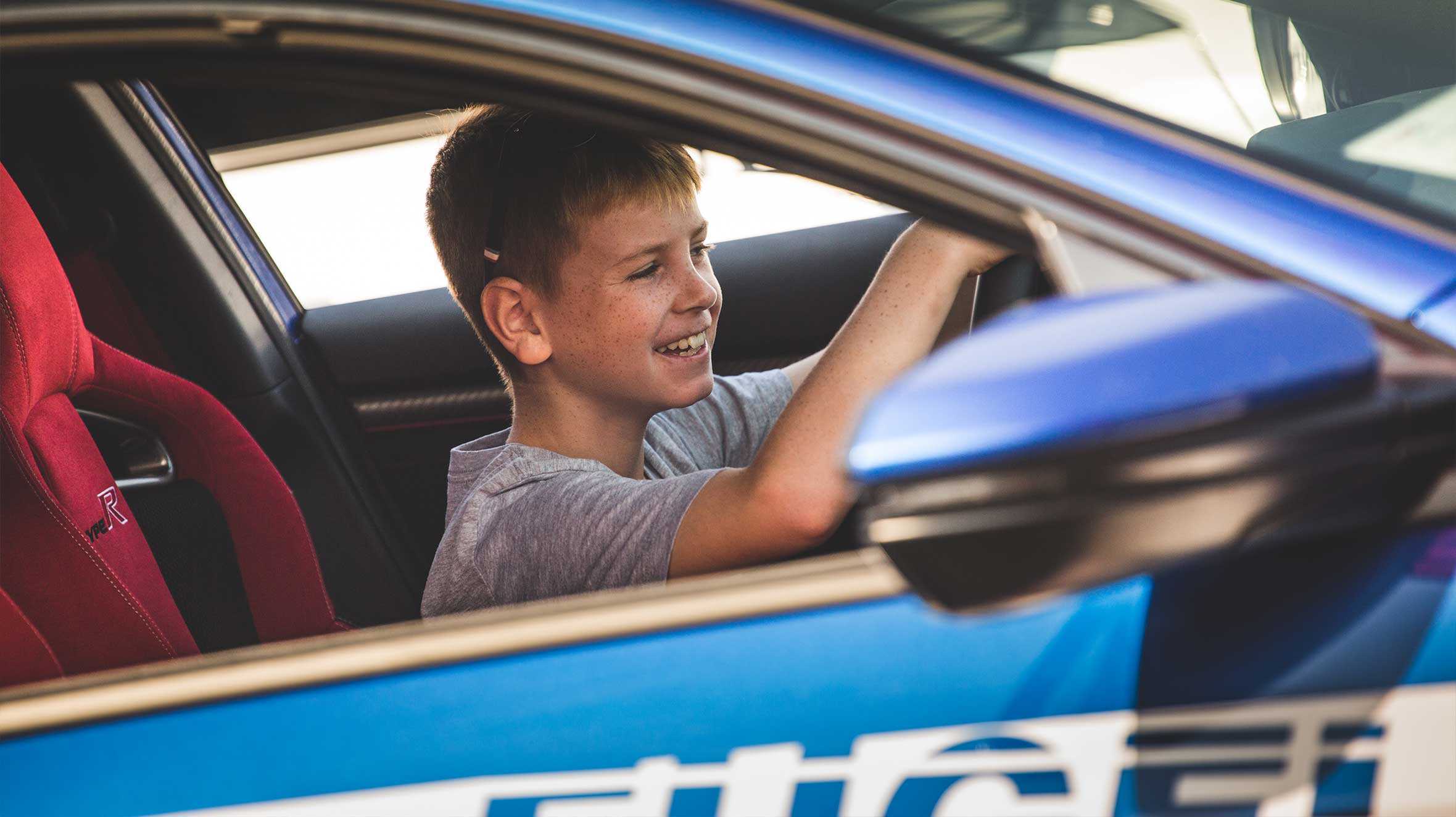 Portrait of Dewi behind steering wheel smiling