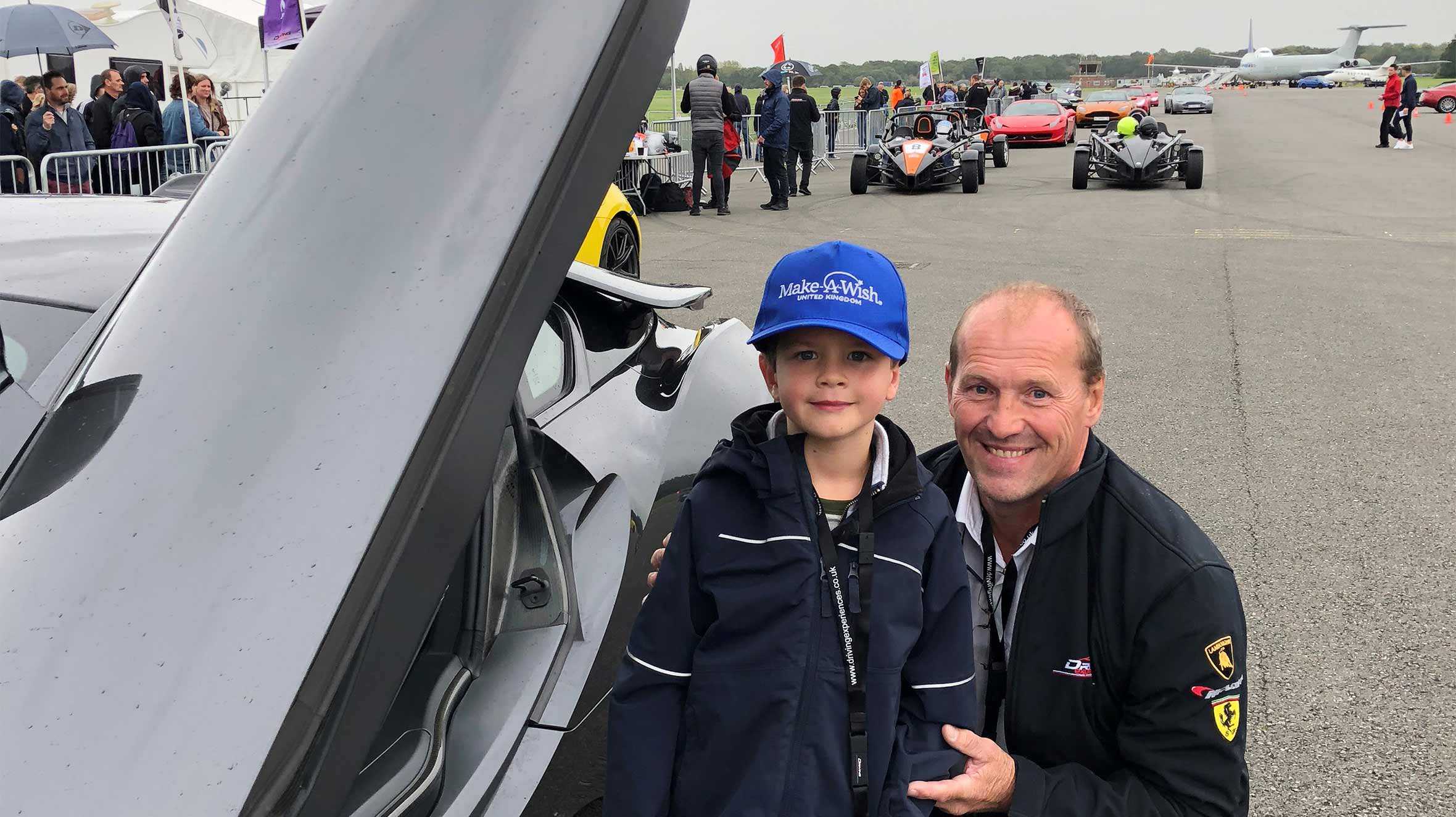 Alex standing by a supercar in the pit lane with Darren from Everyman Racing