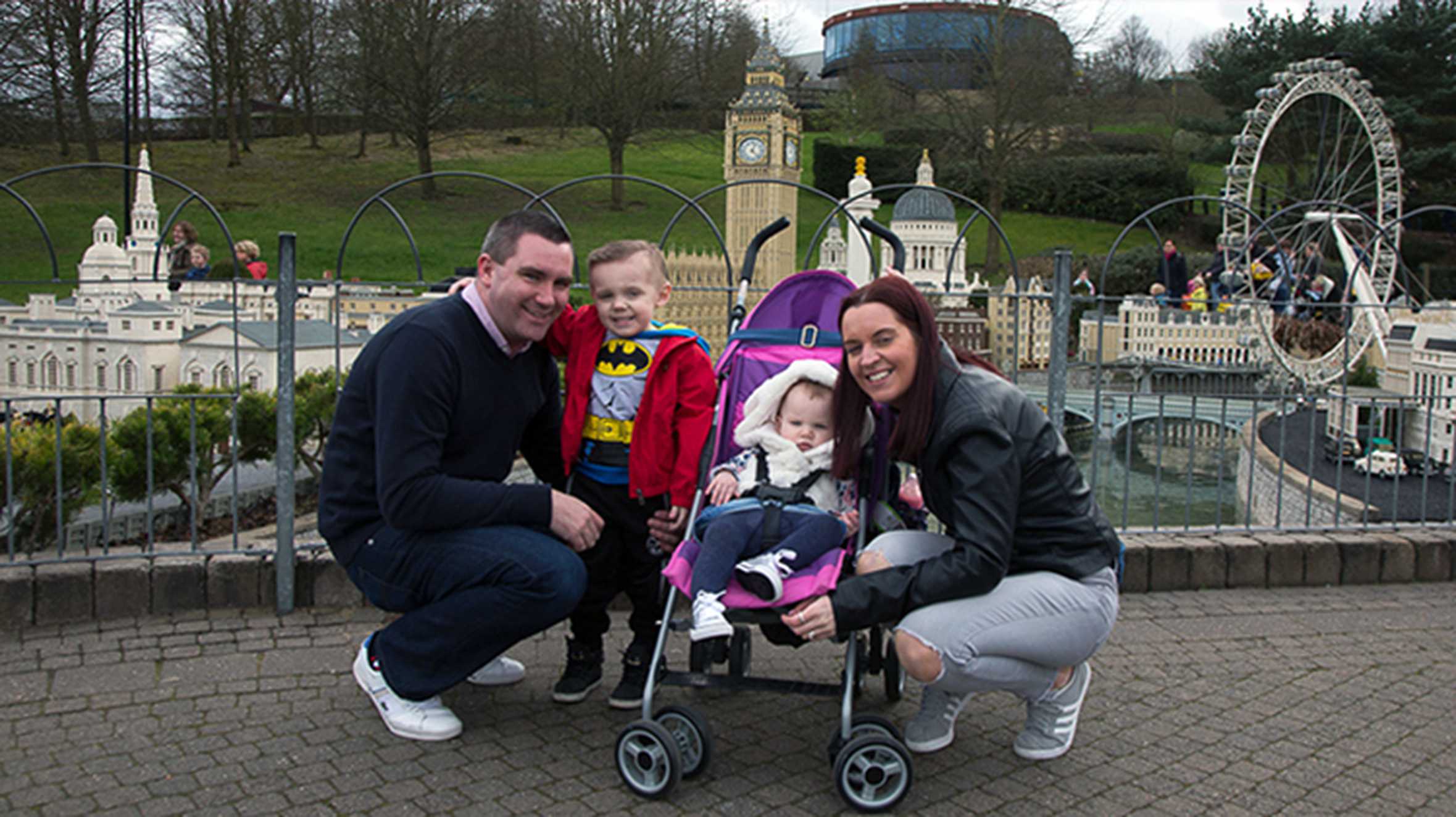 Zak posing in front of Legoland's model village with his mum, dad and sister in a pram.