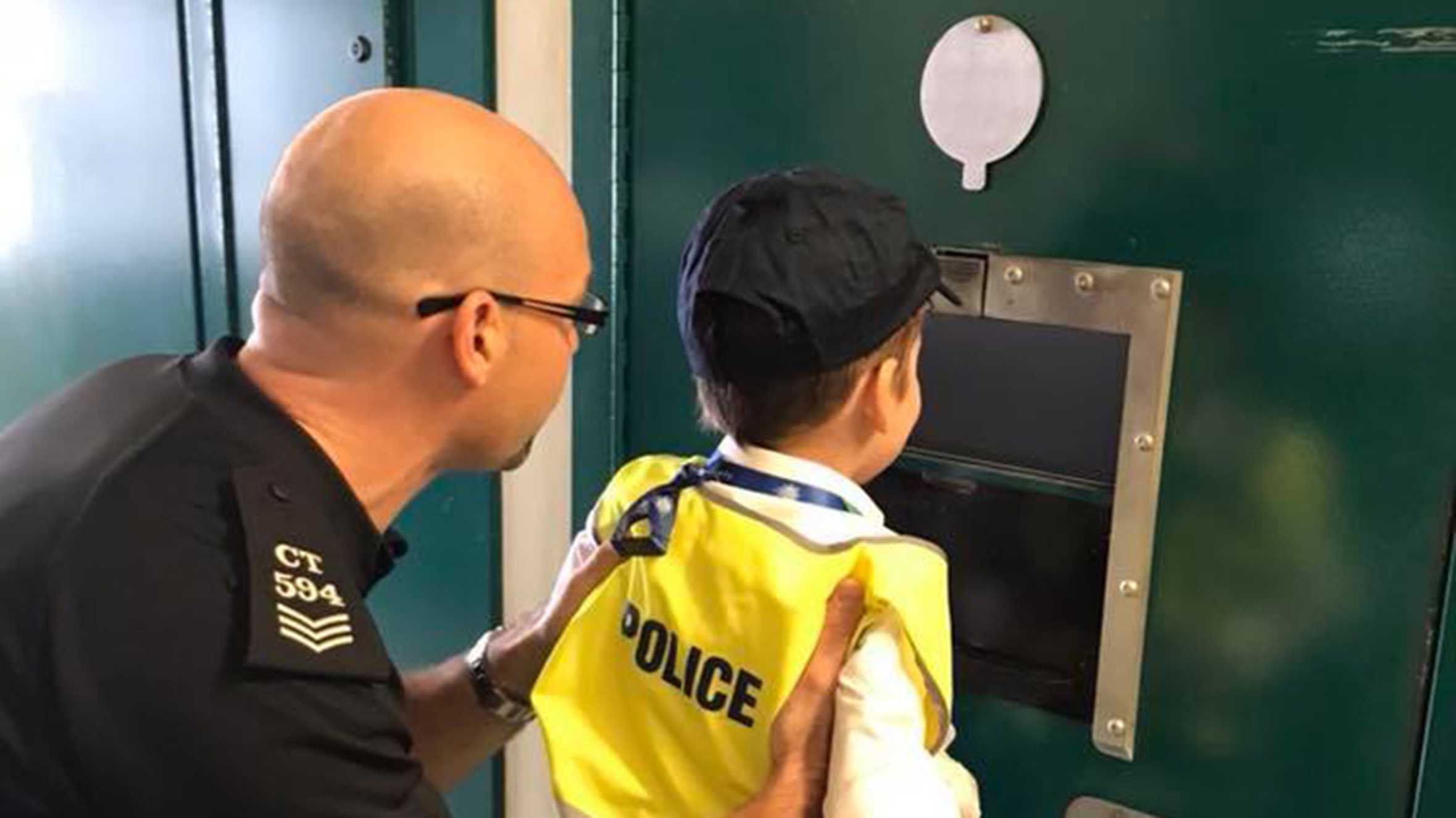 Danny with an officer and being shown inside a police cell
