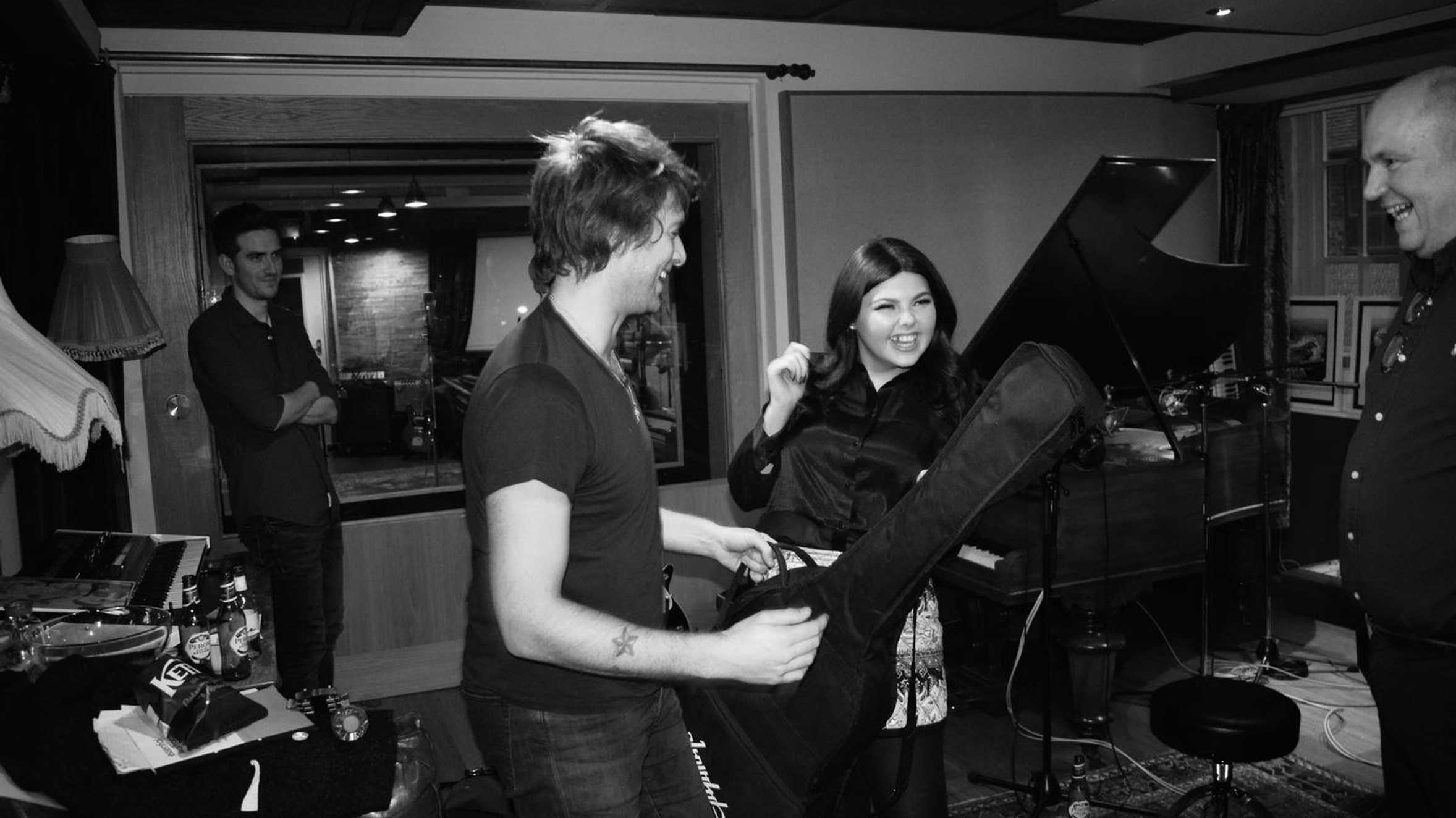 Molly and Paolo Nutini laughing together in front of a piano in his music studio.