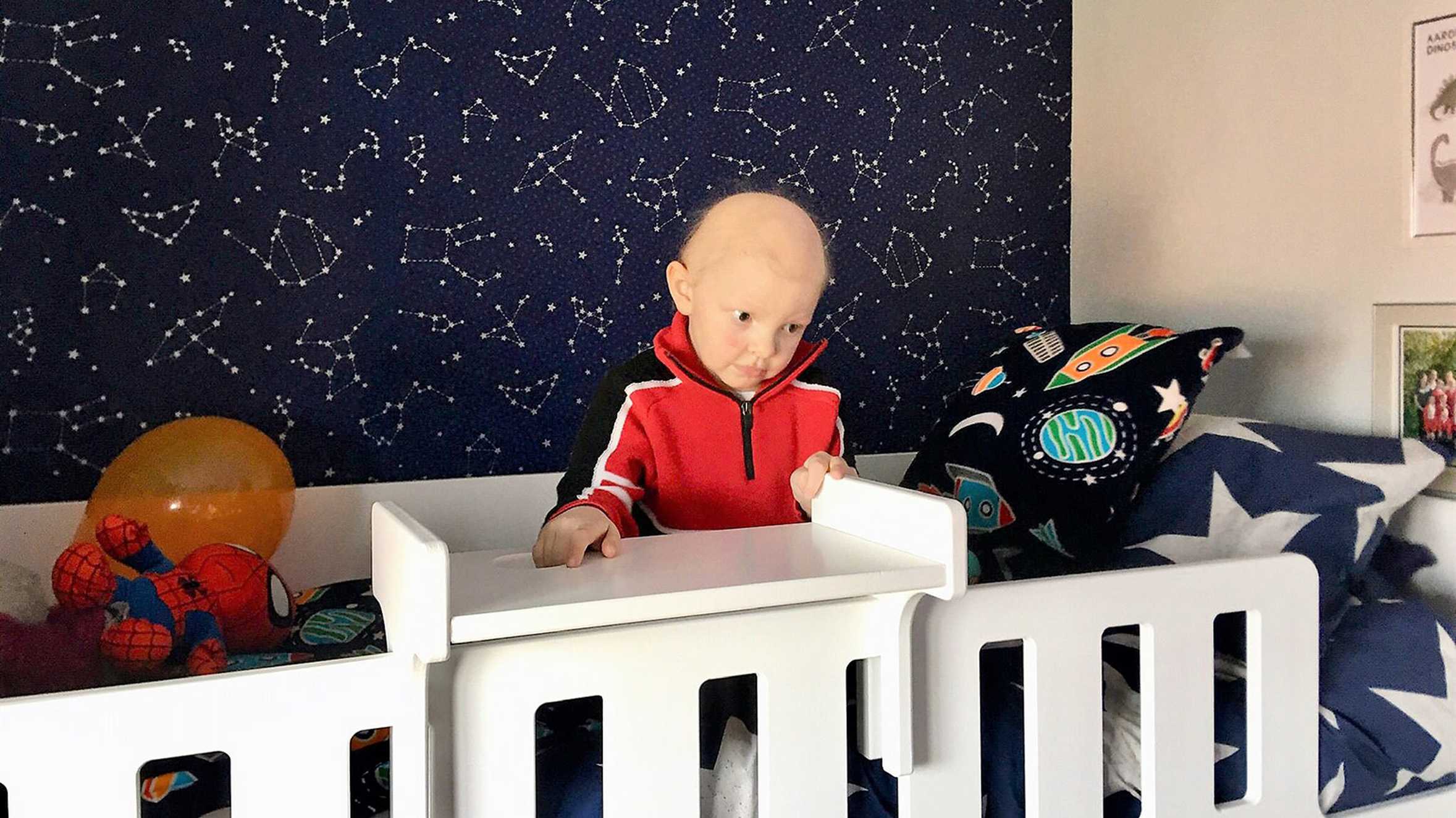 Aaron giving sitting on his new cabin bed with his starry wallpaper in the background.