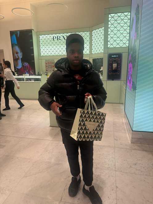 Rayondre holds a paper shopping bag inside a store