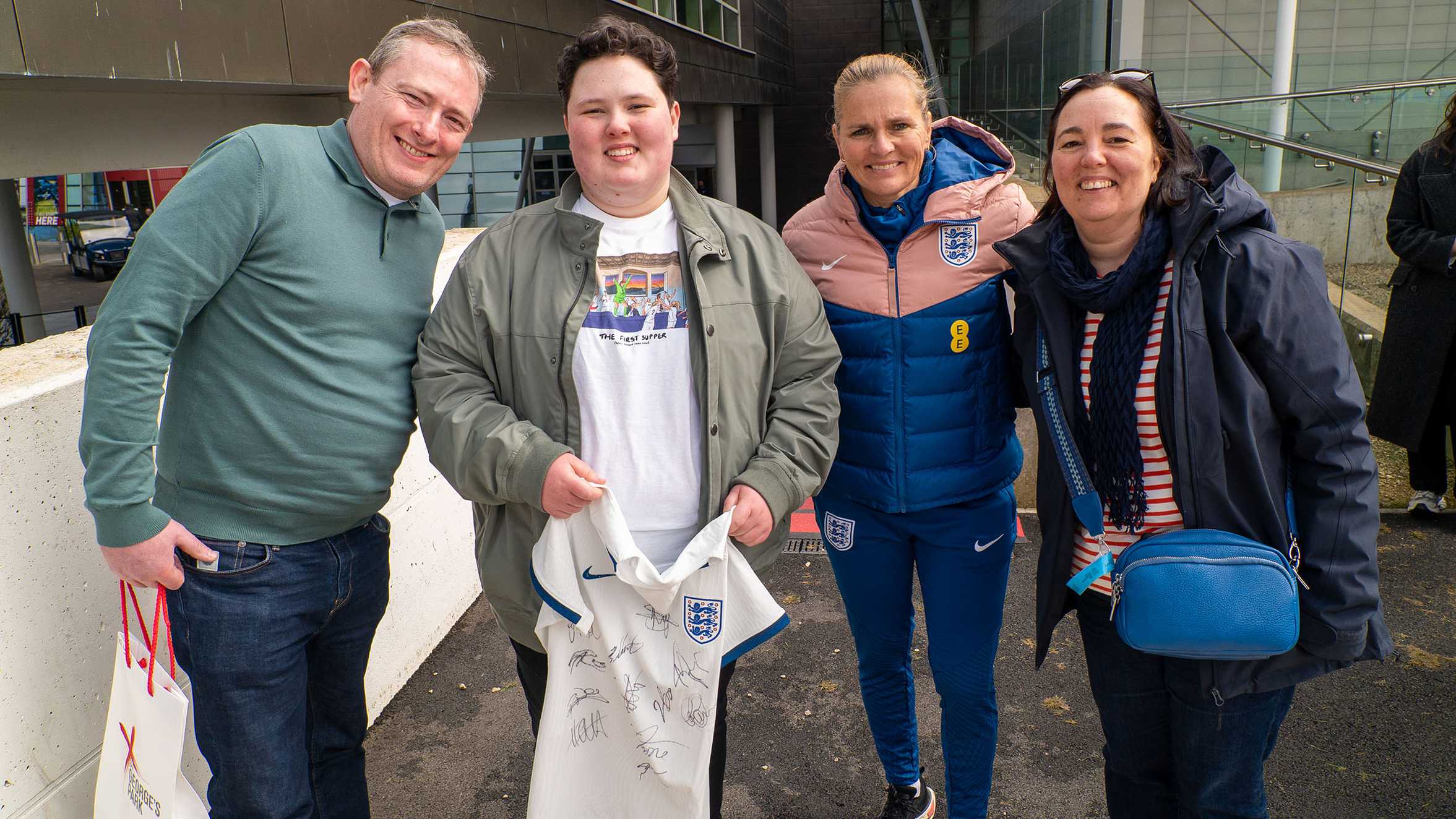 Laura, her mum and dad pose for a photo with England manager Sarina Wiegman