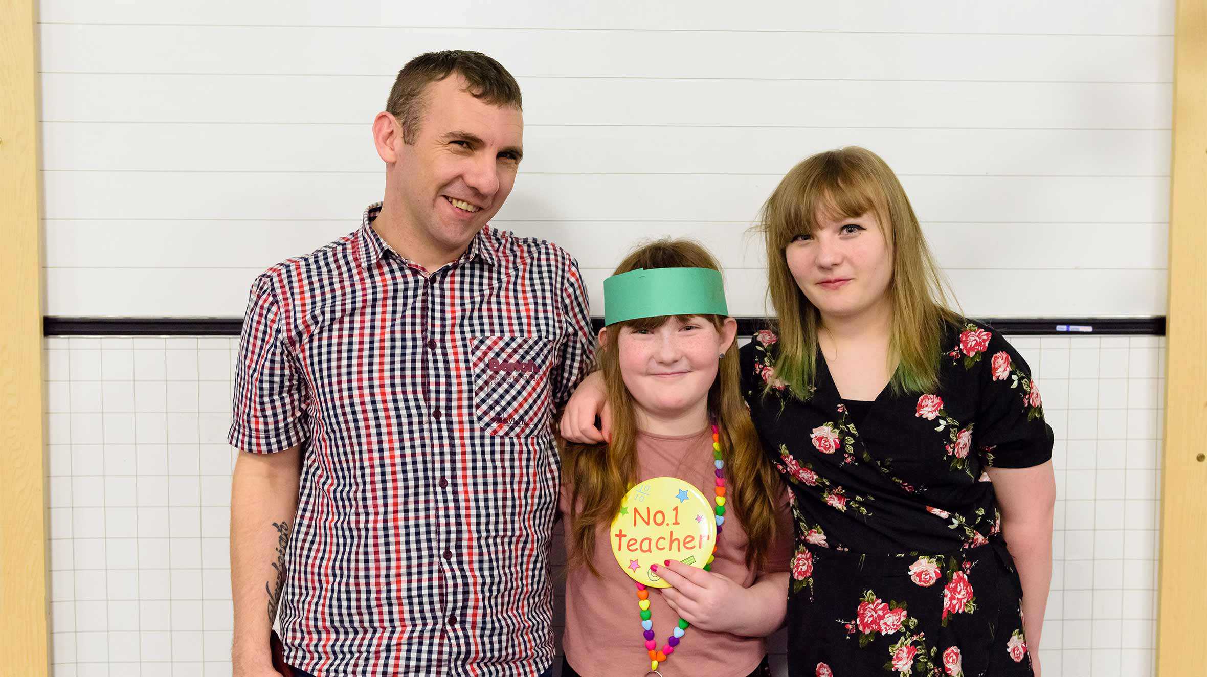 Sarah with her parents, holding her No. 1 teacher badge