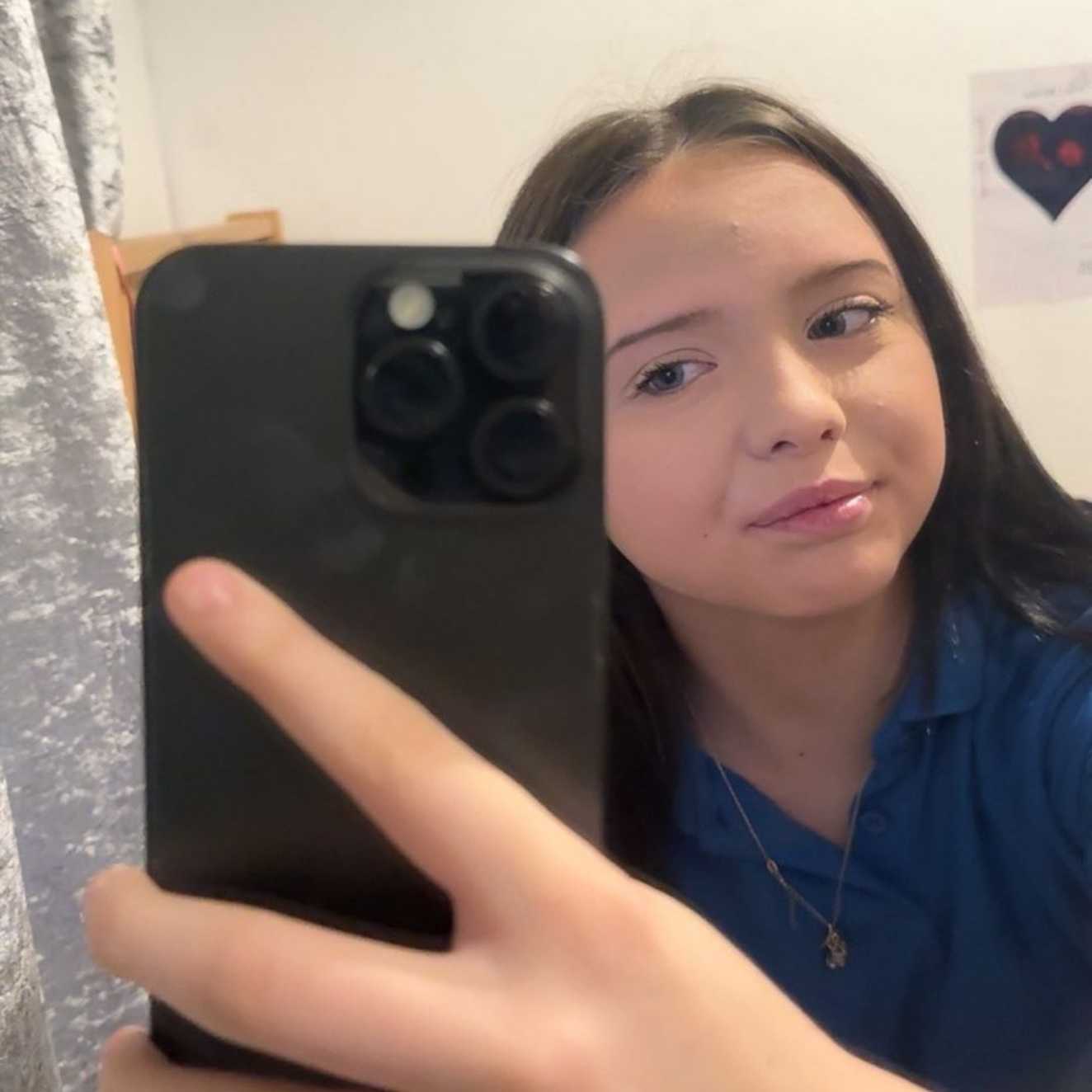 Rosie holding a smartphone taking a selfie, looking into the camera.