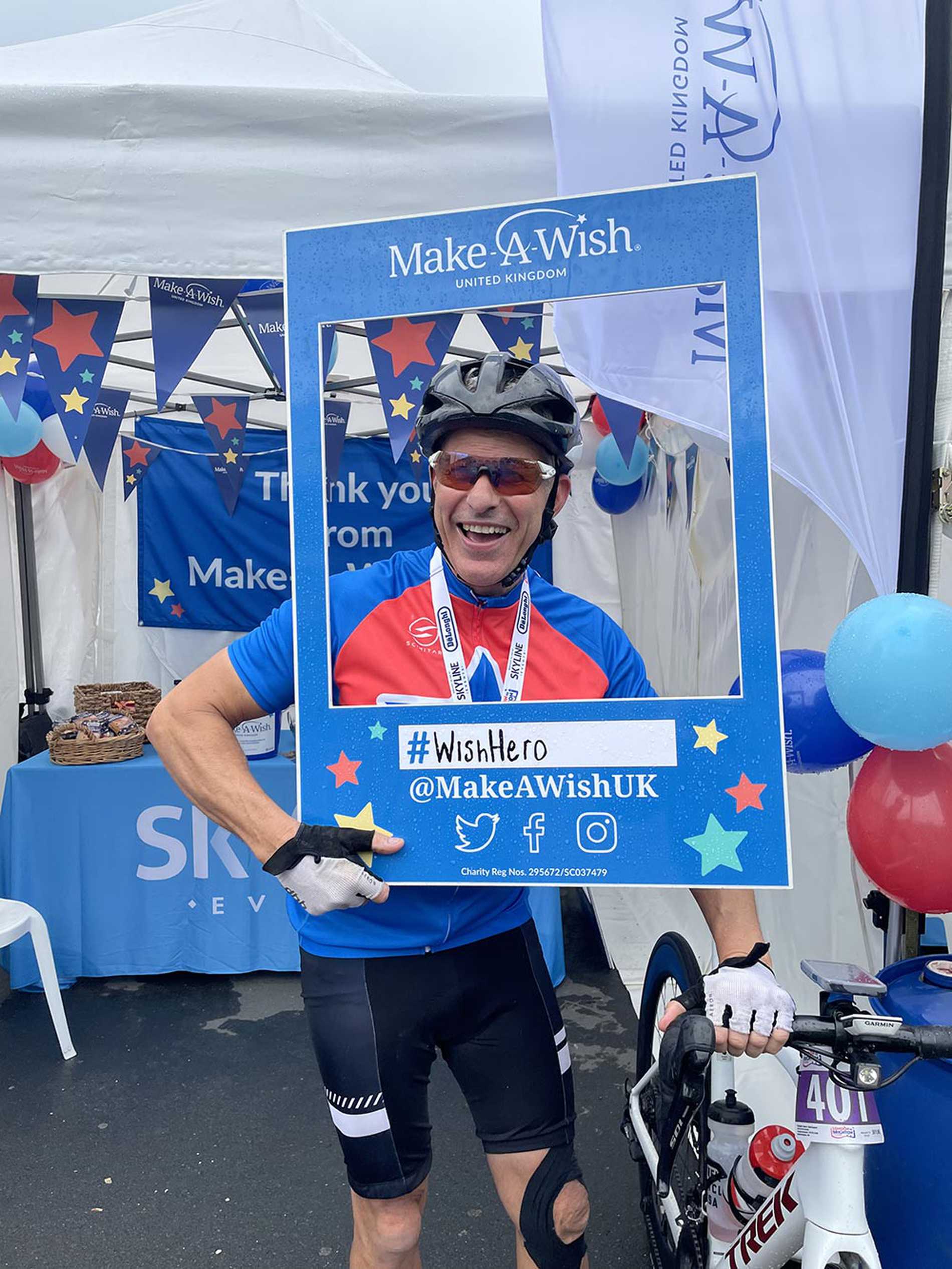 A #WishHero posing with a Make-A-Wish selfie frame after completing the 2021 London to Brighton Cycle challenge.