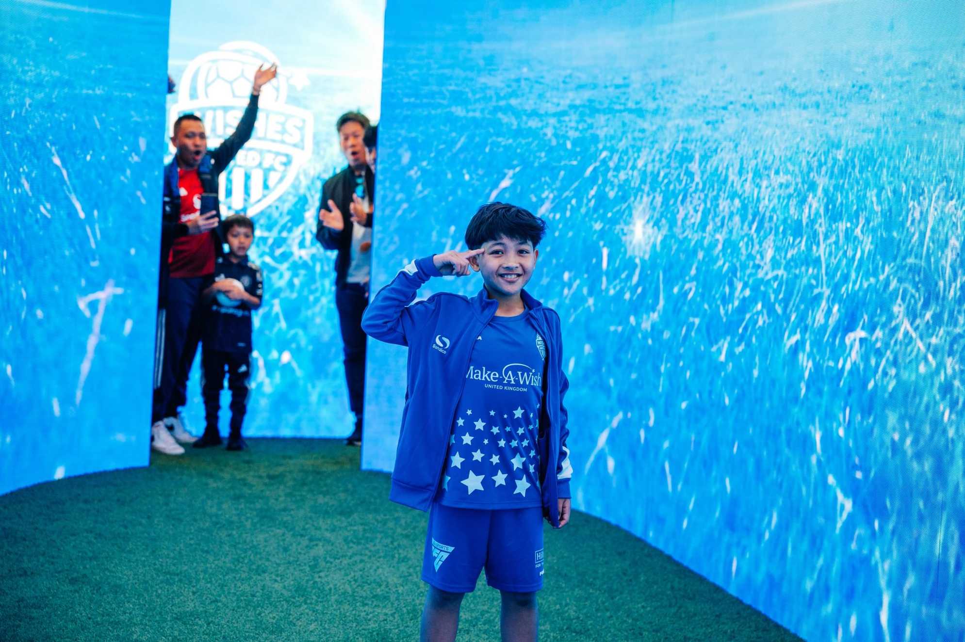 Liam points at his head, replicating a football celebration in the entrance tunnel at Wishes United
