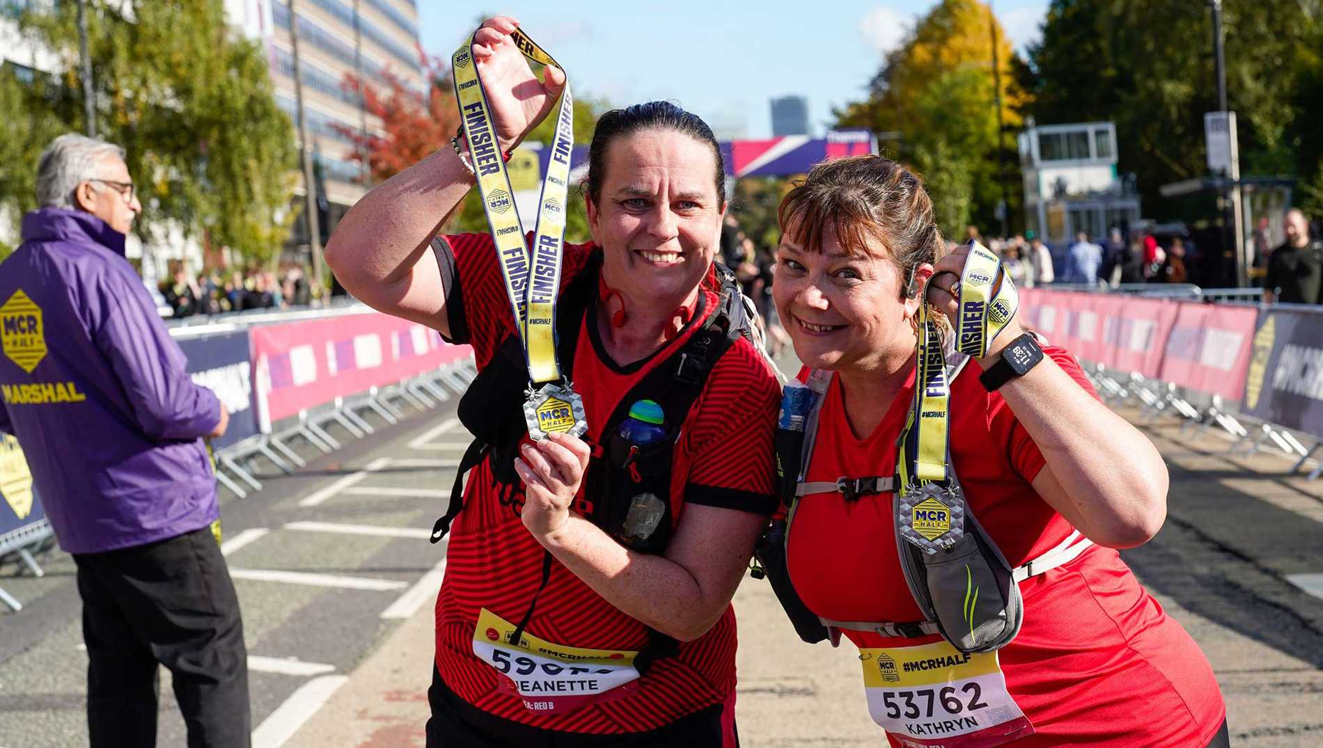 Two Manchester Half Marathon finishers proudly showing off their medals.