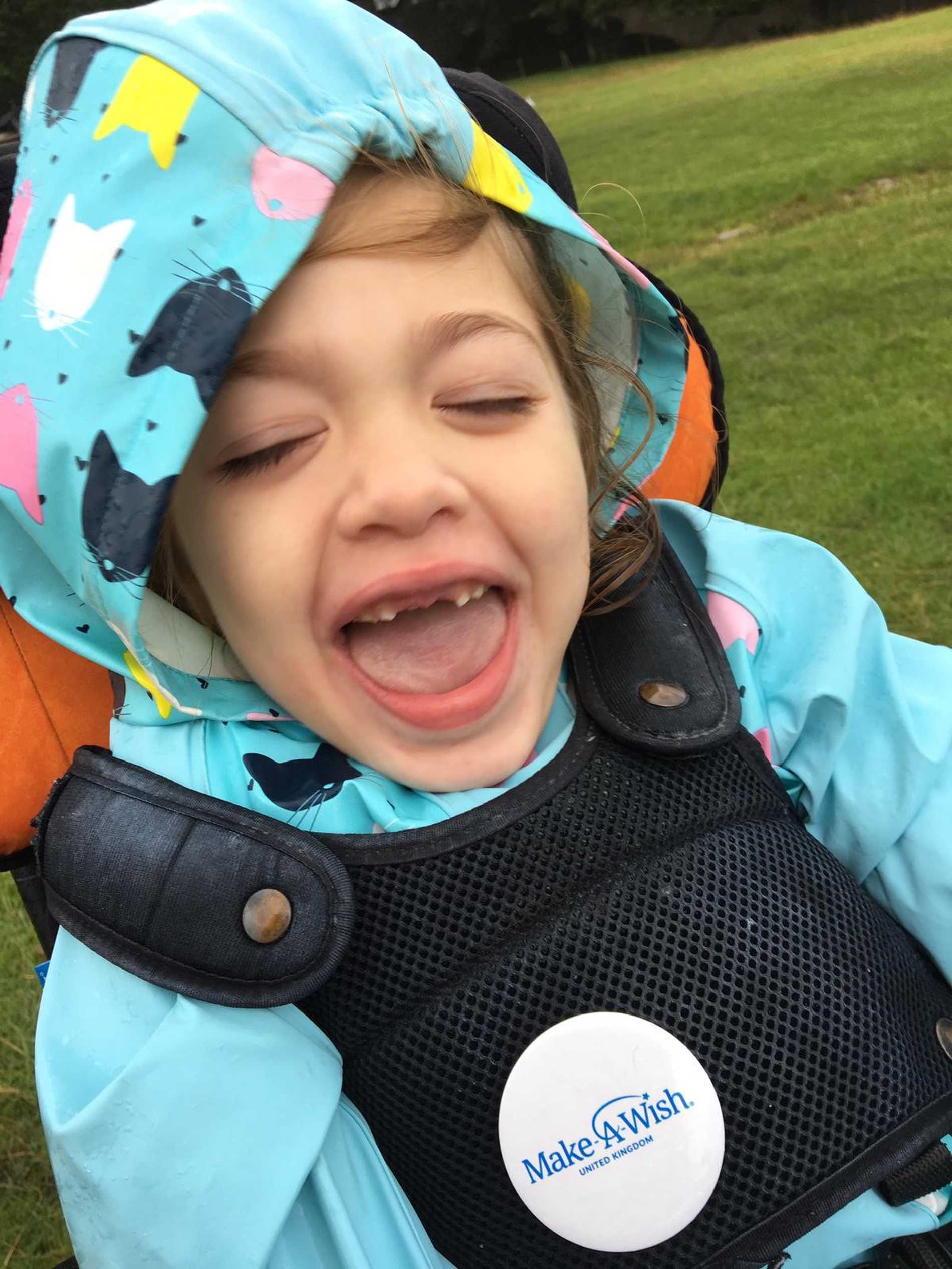 A close up of Aubree in a colourful raincoat with a big smile on her face.