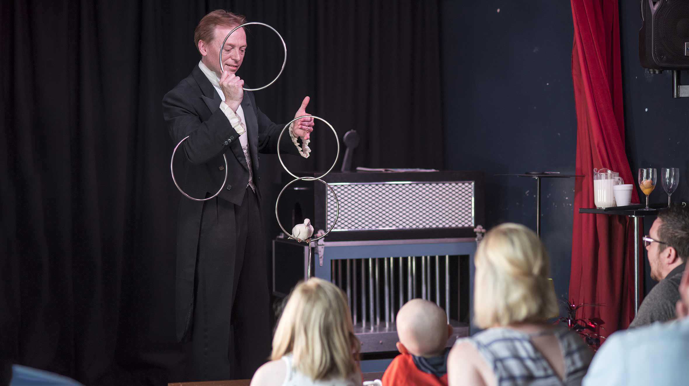 A magician performing a ring trick while Dexter watches on