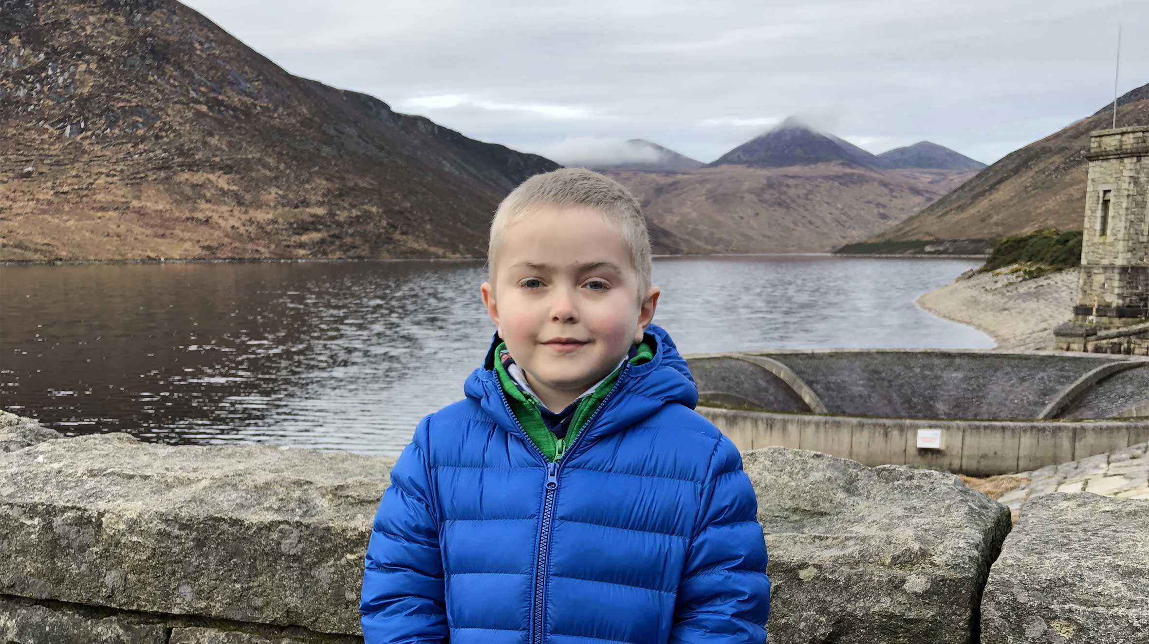 Caden standing in front of a reservoir in a blue jacket