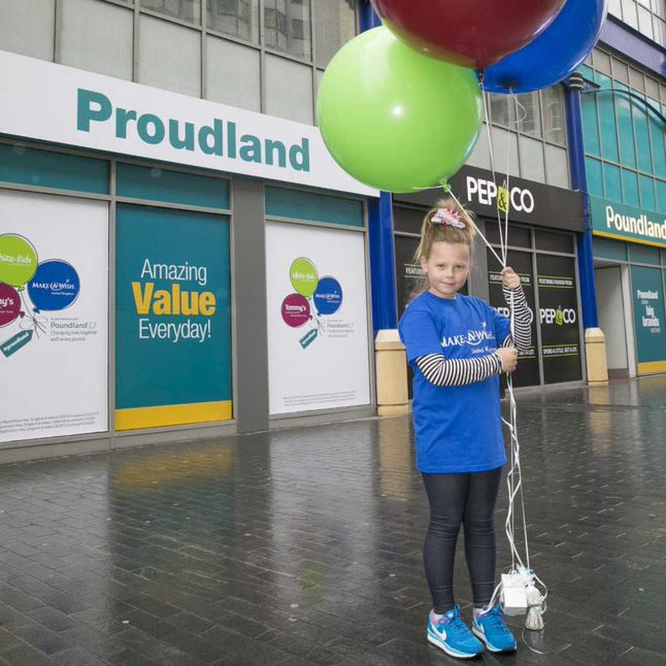 Child with balloons outside a Pounland store
