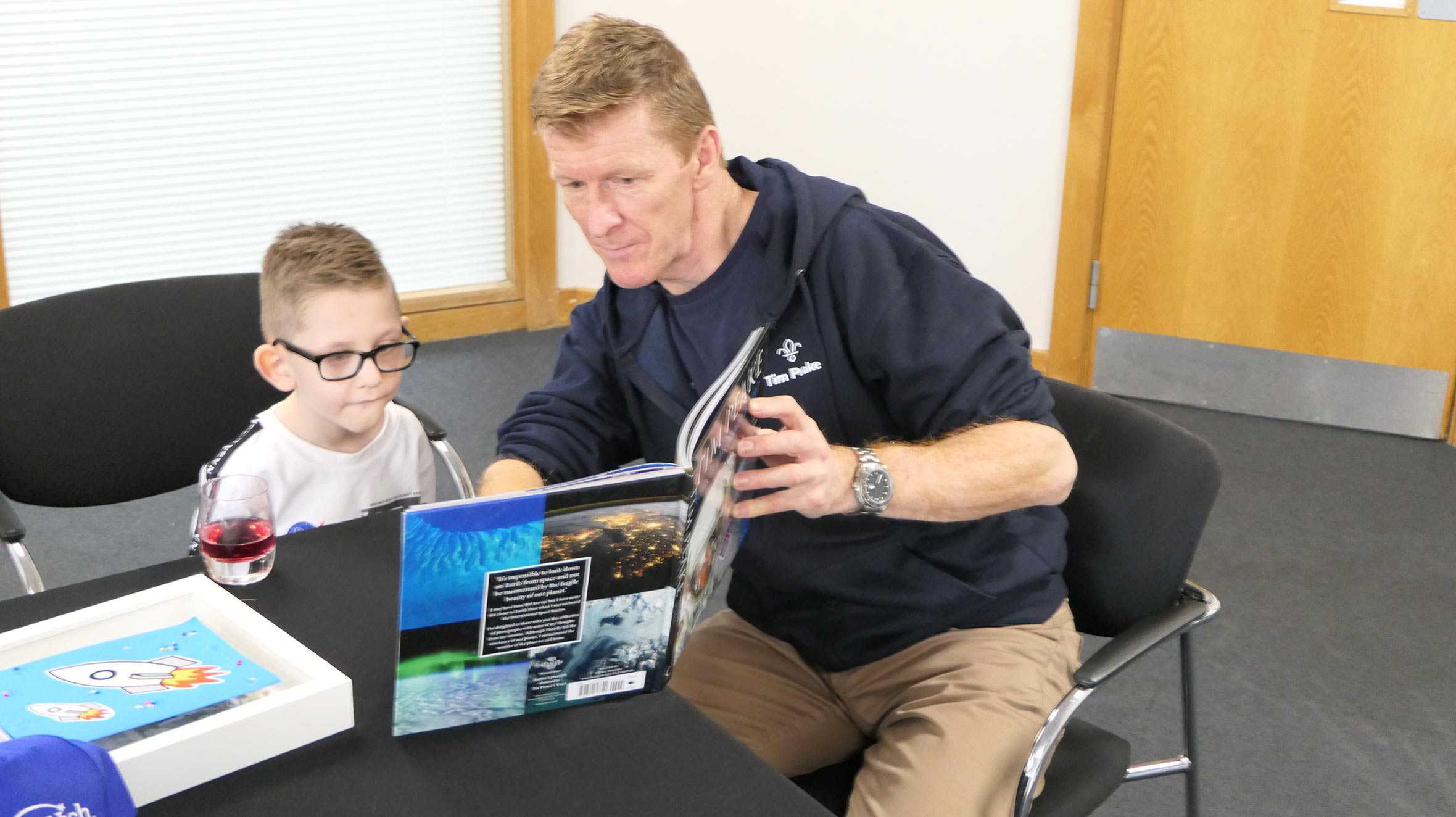 Tim Peake showing a book to wish child, Riley.