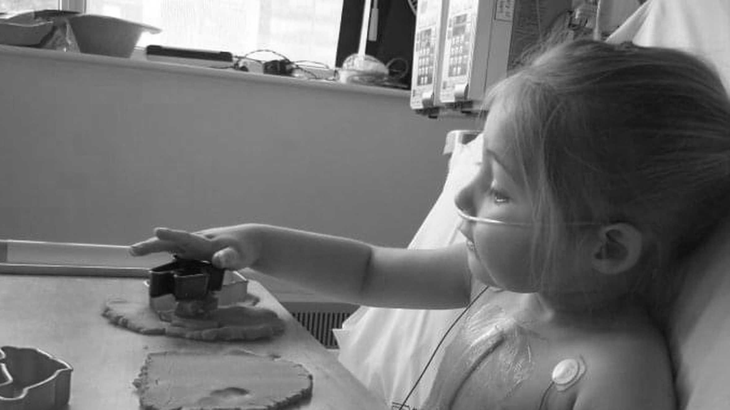 Eloise cutting out shapes with a cookie cutter while in her hospital bed.