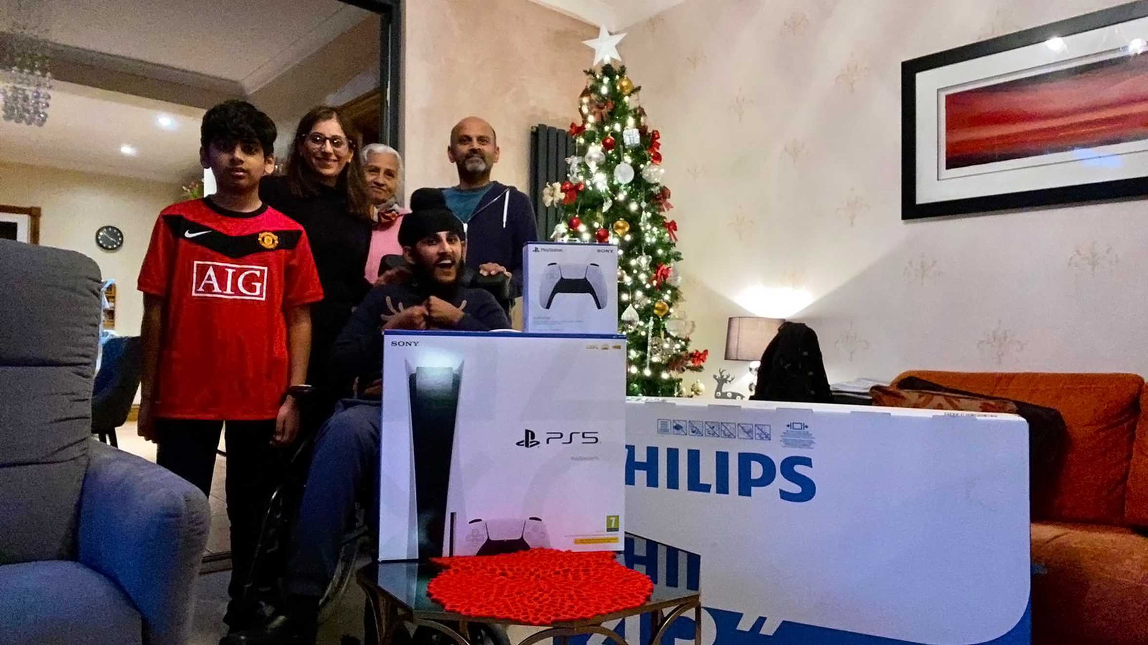 Sunil and his family posing in front of the Christmas tree with his PS5.