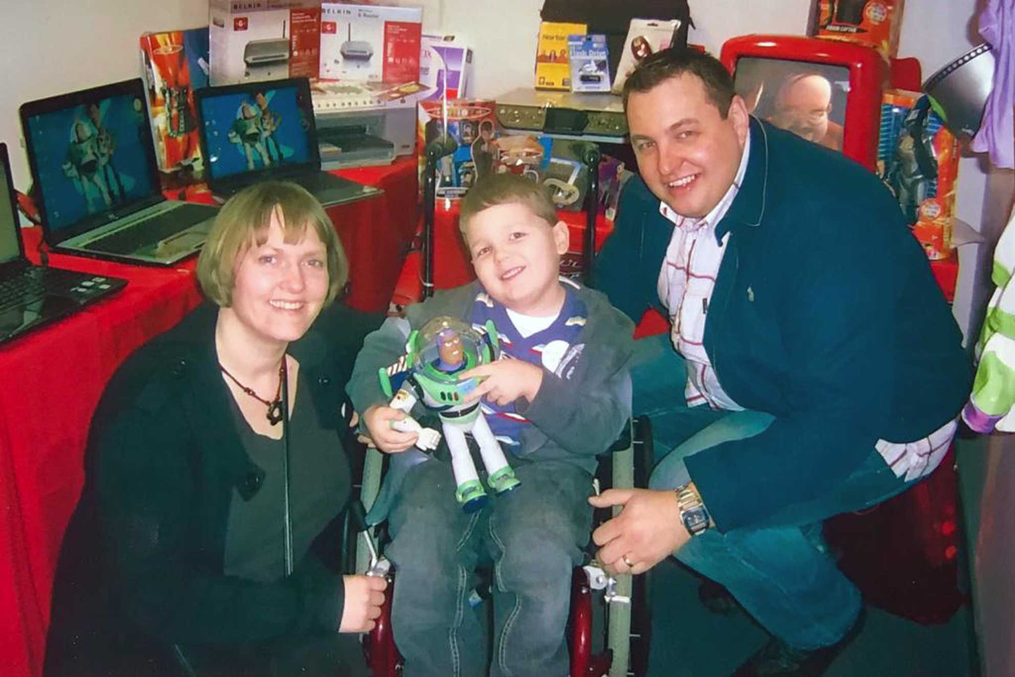 Jacob, holding a Buzz Lightyear doll, with his mum and dad.